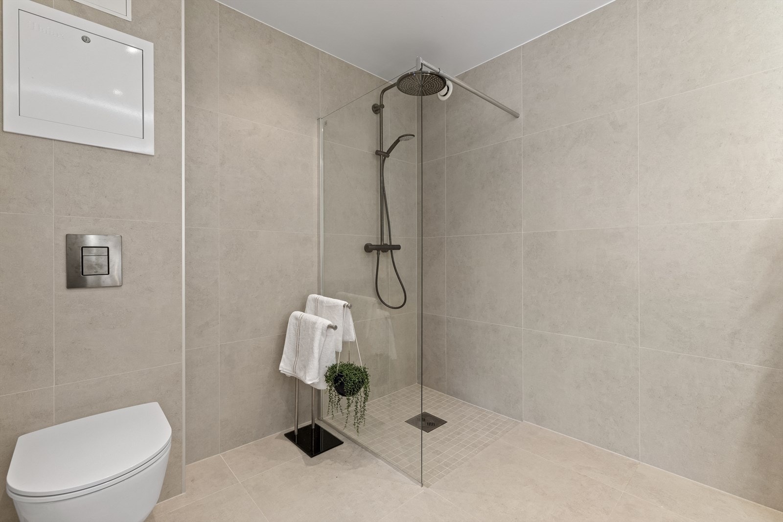 Rommet har dusjhjørne og veggmontert toalett med synlig drensspalte, samt mekanisk avtrekksventilasjon Galleribilde