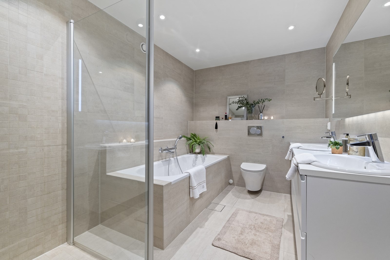 Delikat bad rehabilitert i 2017. Flislagte vegger og gulv, samt malte plater i himling med downlights. Badet har innmurt badekar med flislagt front, to servanter med underskap og blandebatterier, samt veggmontert toalett Galleribilde