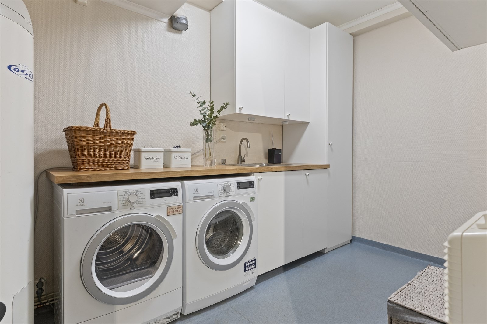 Vaskerom med lagring, brettebenk og opplegg til vaskemaskin og tørketrommel. Varmtvannsberederen til venstre i bildet ble nettopp skiftet til en ny 300-liters bereder Galleribilde