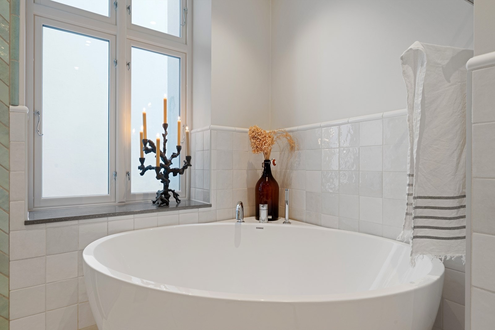 Badet utstyrt med servantinnredning, toalett, et stort badekar samt dusjvegger i glass. Det er også installert elektrisk styrt vifte for ventilasjon. Galleribilde