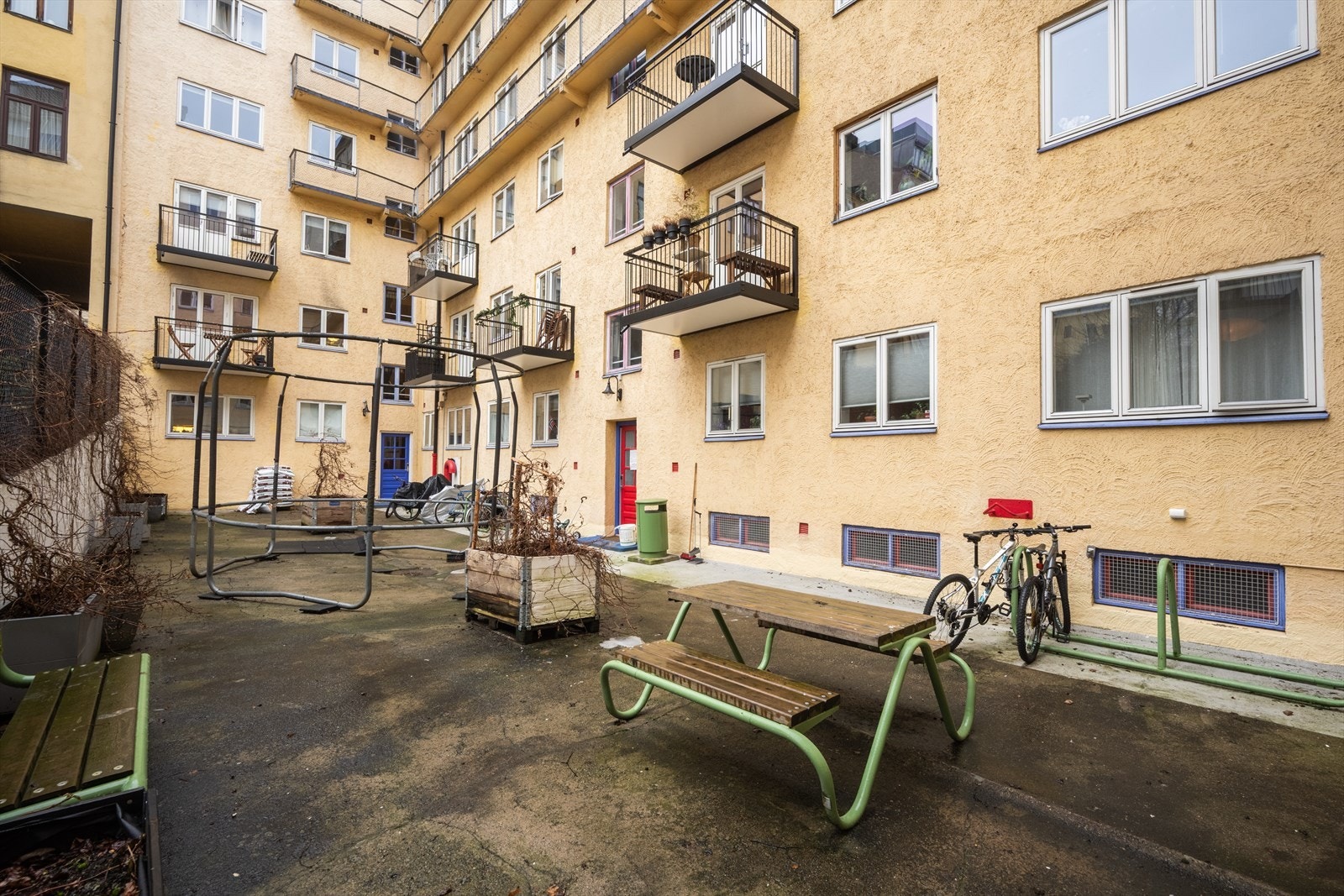 Lukket bakgård med sykkelparkering, sittegrupper og trampoline. Galleribilde