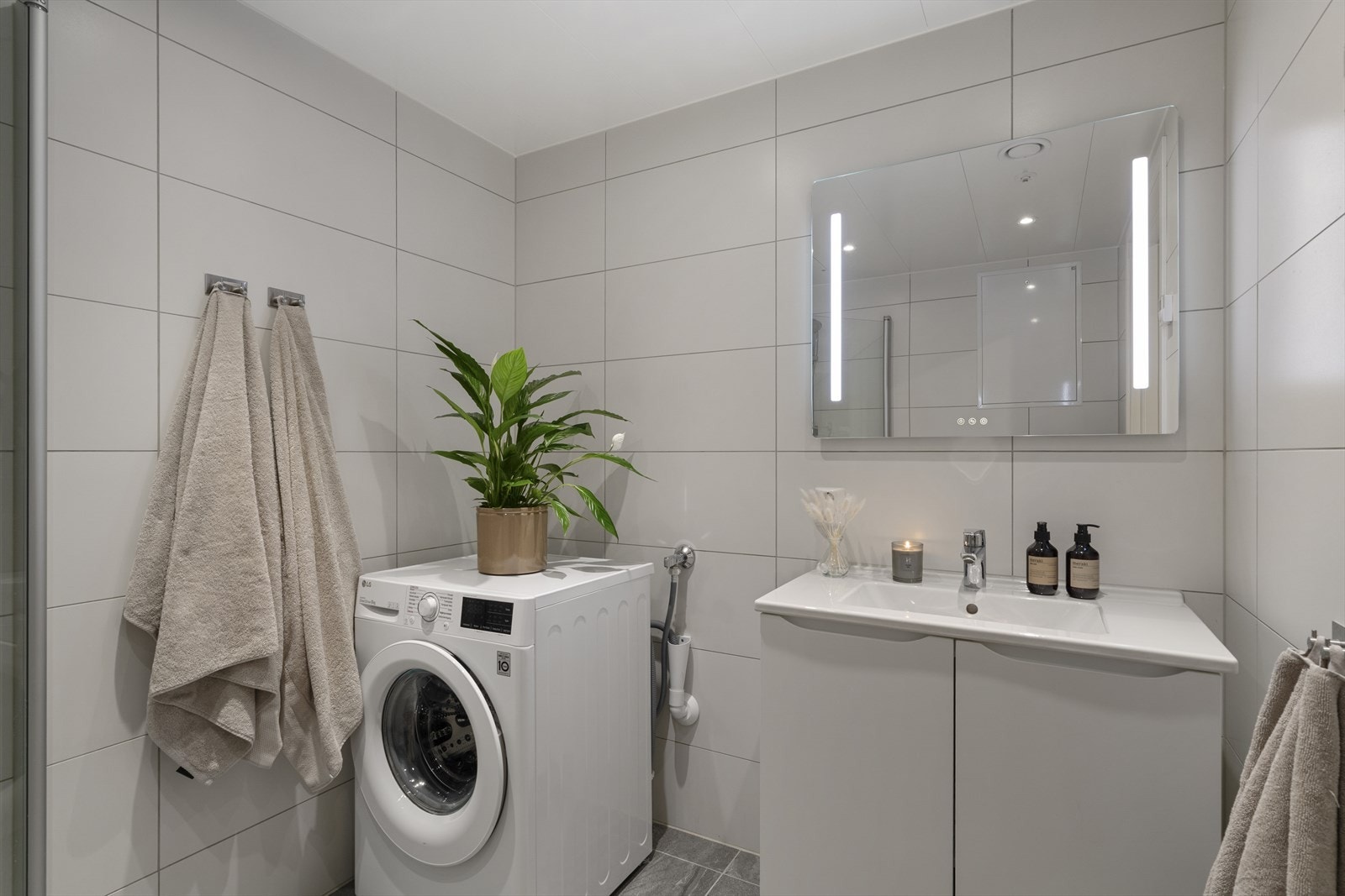 På bad er det flislagte gulv og vegger, innfellbare dusjdører, vegghengt klosett, baderomsinnredning og opplegg for vaskemaskin. Galleribilde