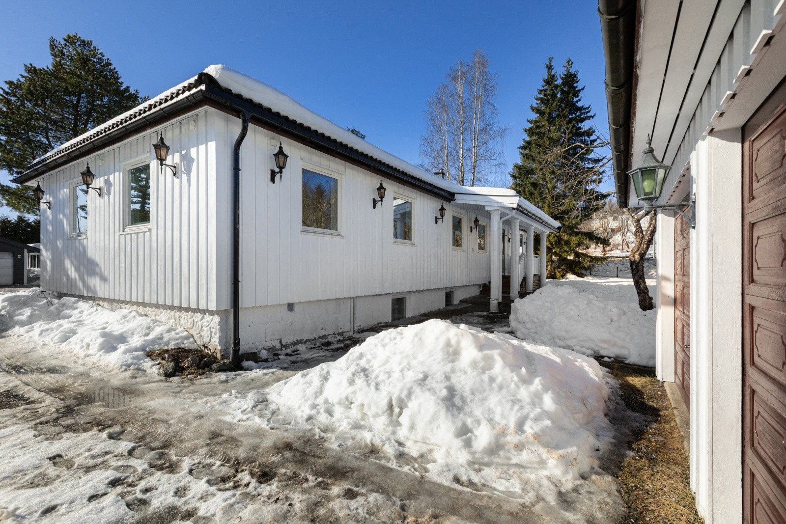 Store deler av innkjørselen er gruslagt. Det er en sti med heller fra garasjen til hovedveien. Foran inngangspartiet er det steinbelagt. Galleribilde