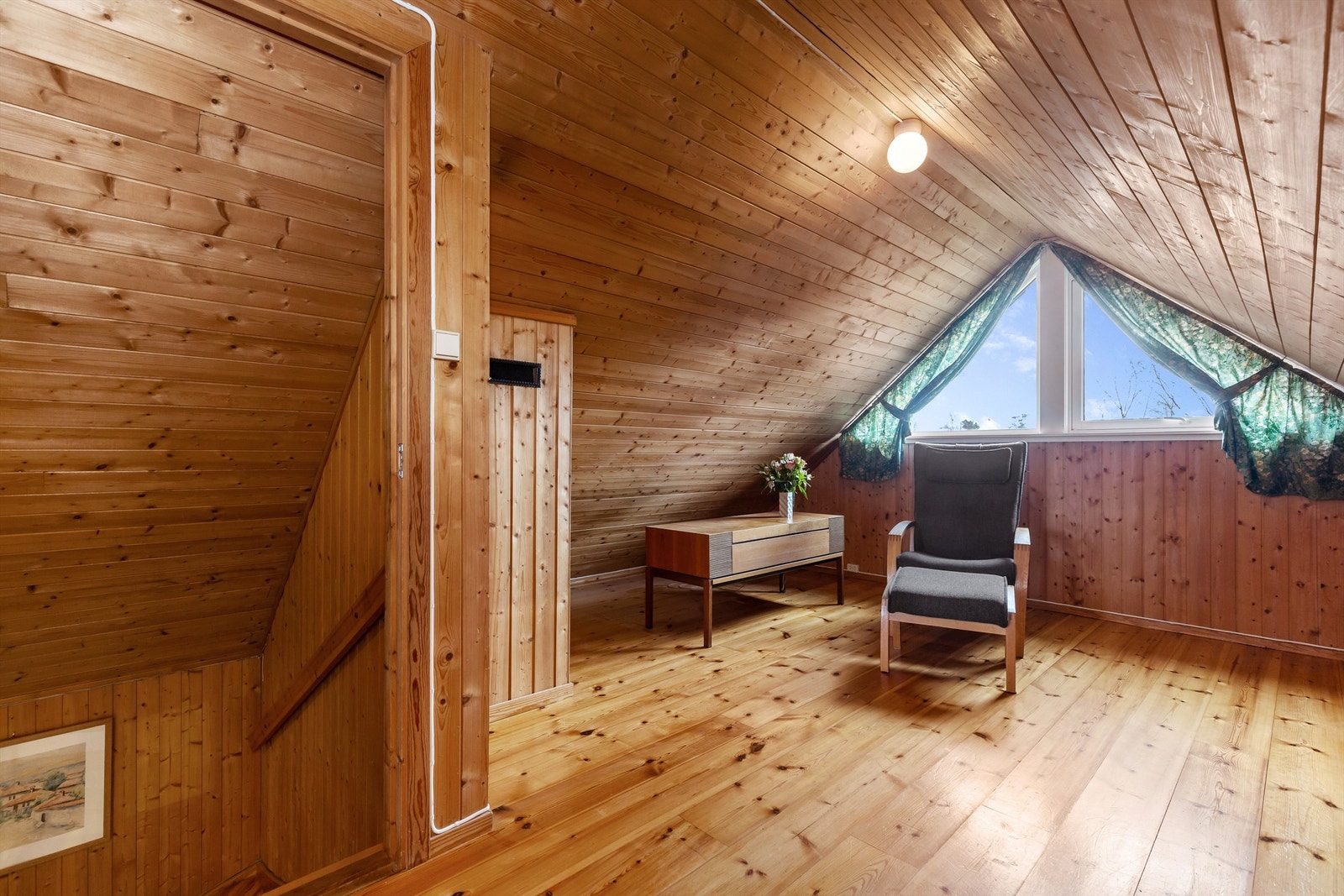 Innredet loftstue med heltre gulv og panel på vegger og i tak. Galleribilde