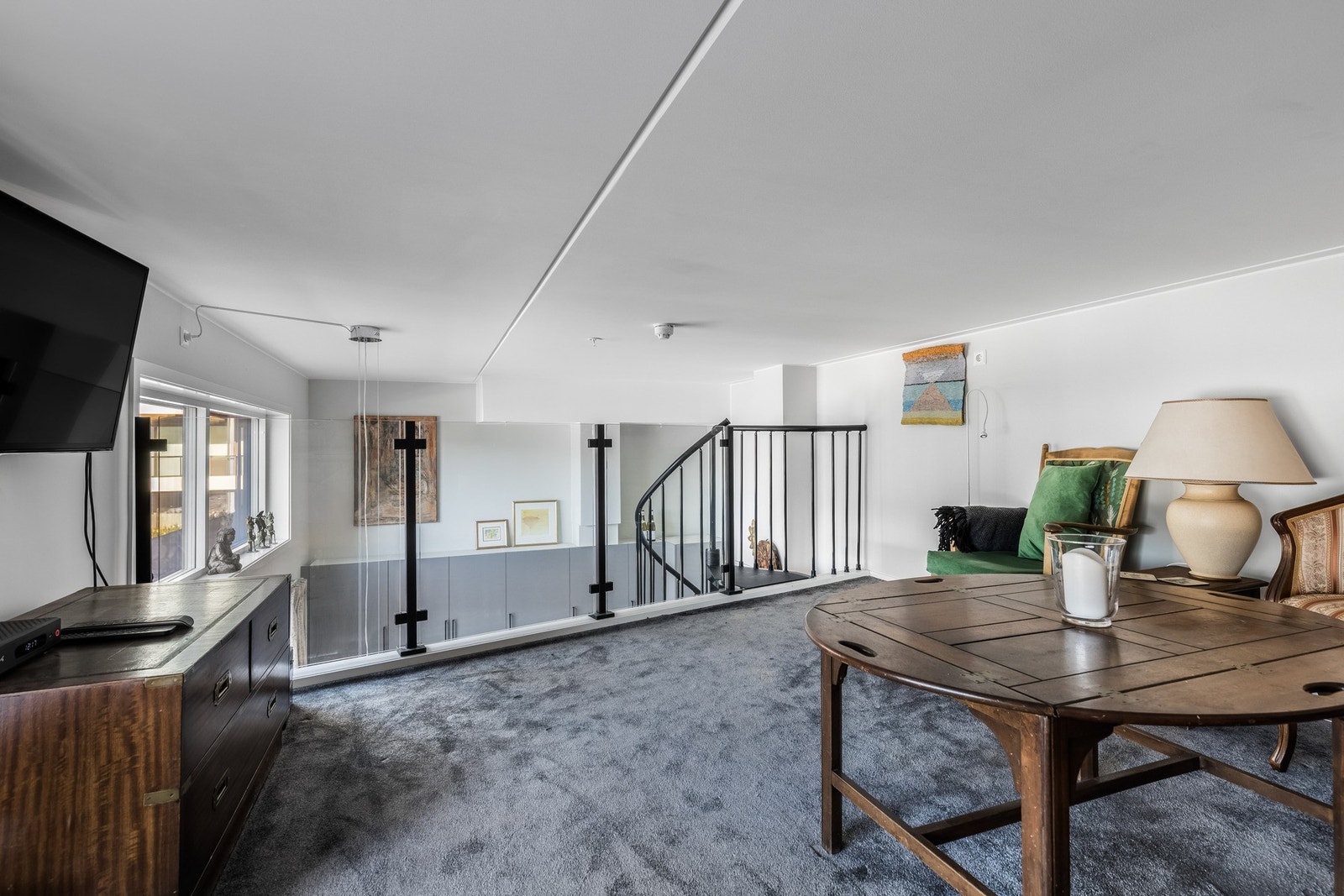 Mesanin er innrammet med glassrekkverk. Galleribilde