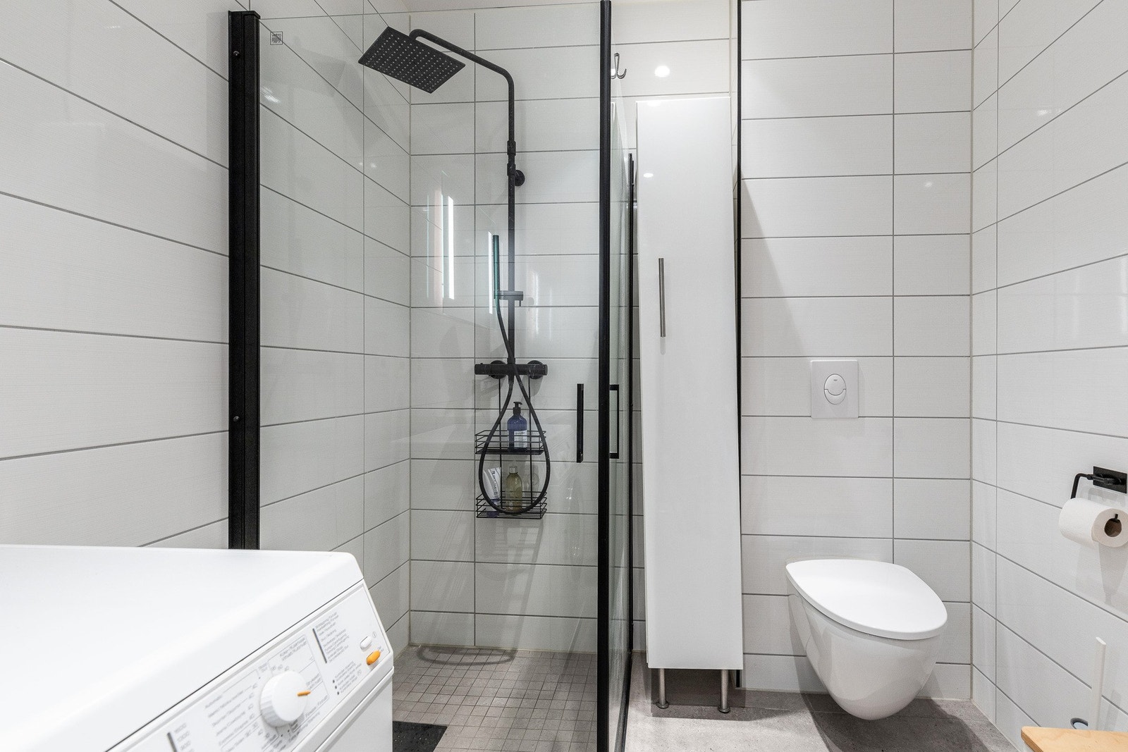 Baderommet er utstyrt med dusjhjørne med regnfallsdusj, veggmontert wc, servant med speil og belysning samt opplegg for vaskemaskin og tørketrommel. Galleribilde