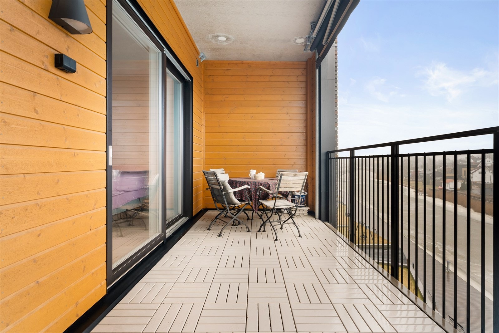 Balkongen har betongdekke med PVC-fliser og et stilrent rekkverk i aluminium. Galleribilde