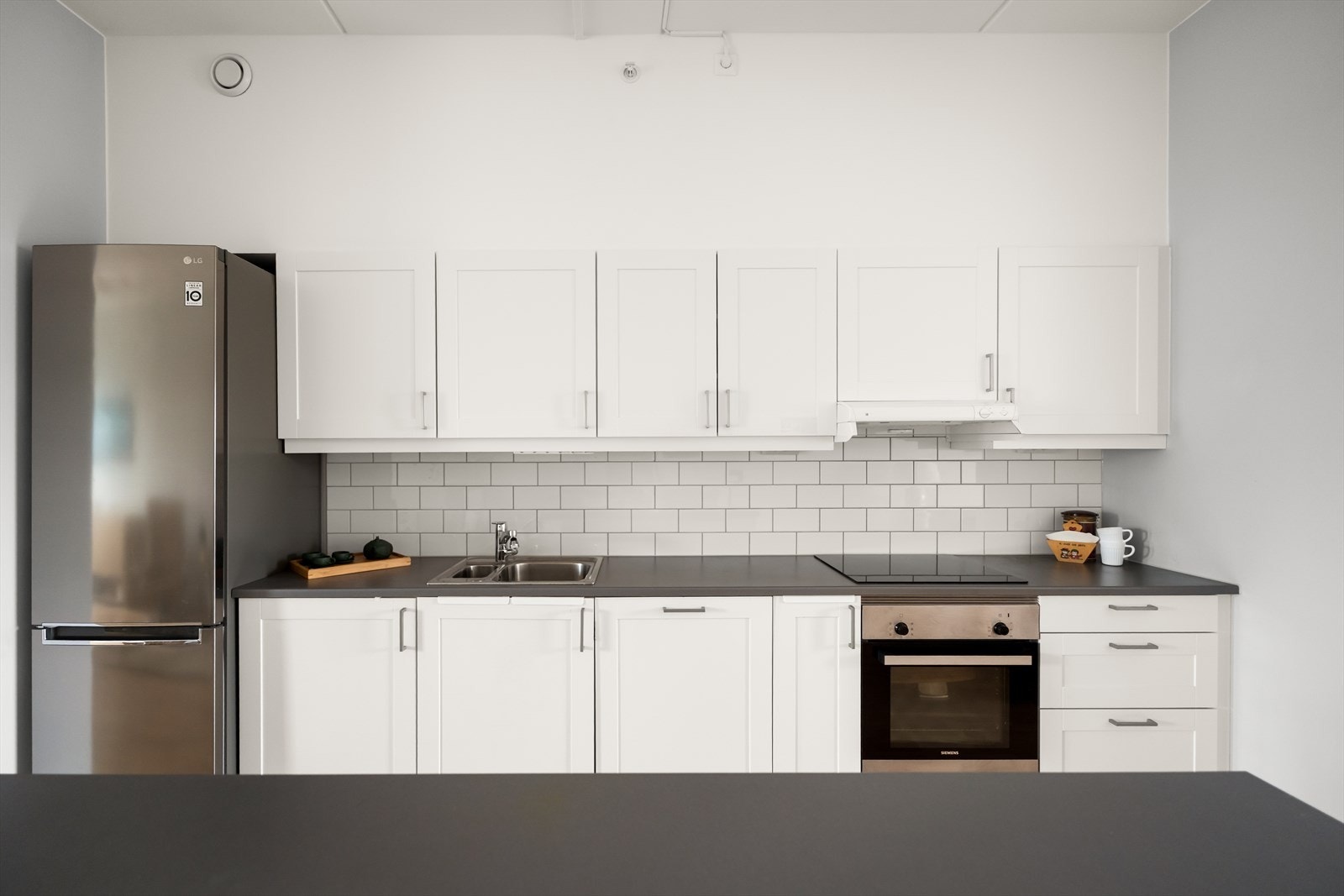 Moderne Sigdal-kjøkken fra 2021 med integrert komfyr, induksjonstopp, oppvaskmaskin og kjøl/fryseskap. Galleribilde