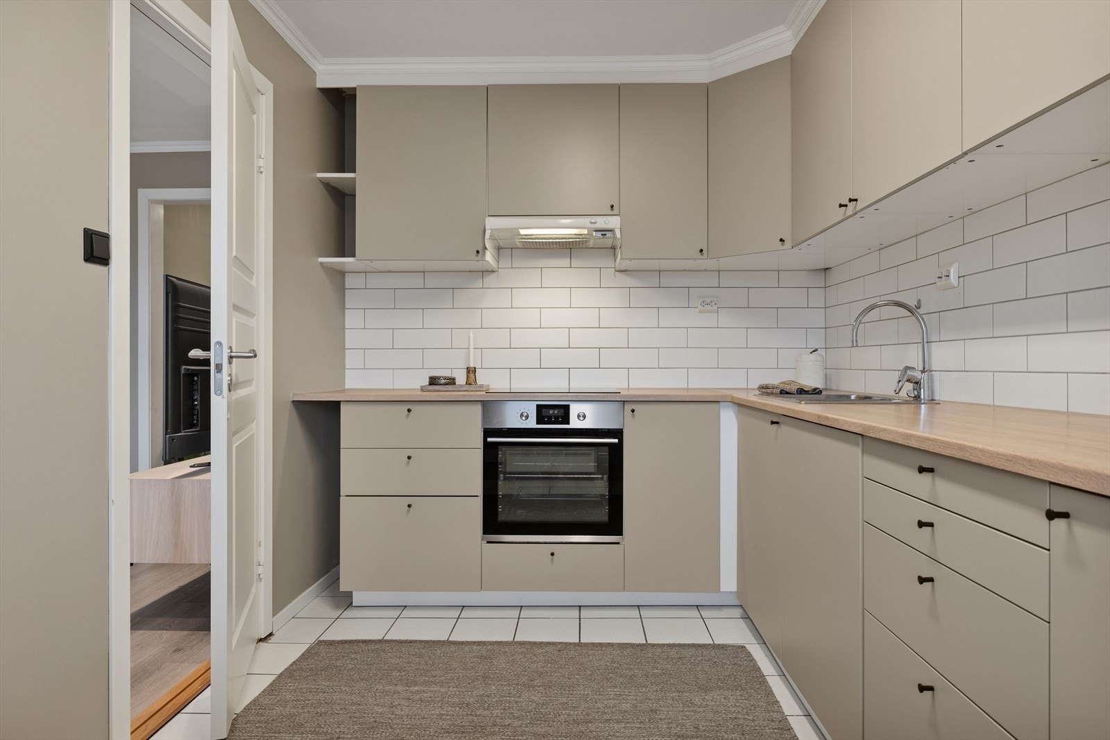 Fliser bak kjøkkenbenk, i tillegg til fliser på gulvet gjør det praktisk å holde det rent med mat- og vannsøl. Kjøkkenet er ellers utstyrt med frittstående kjøleskap, integrert oppvaskmaskin, stekeovn, koketopp og kjøkkenventilator. Galleribilde