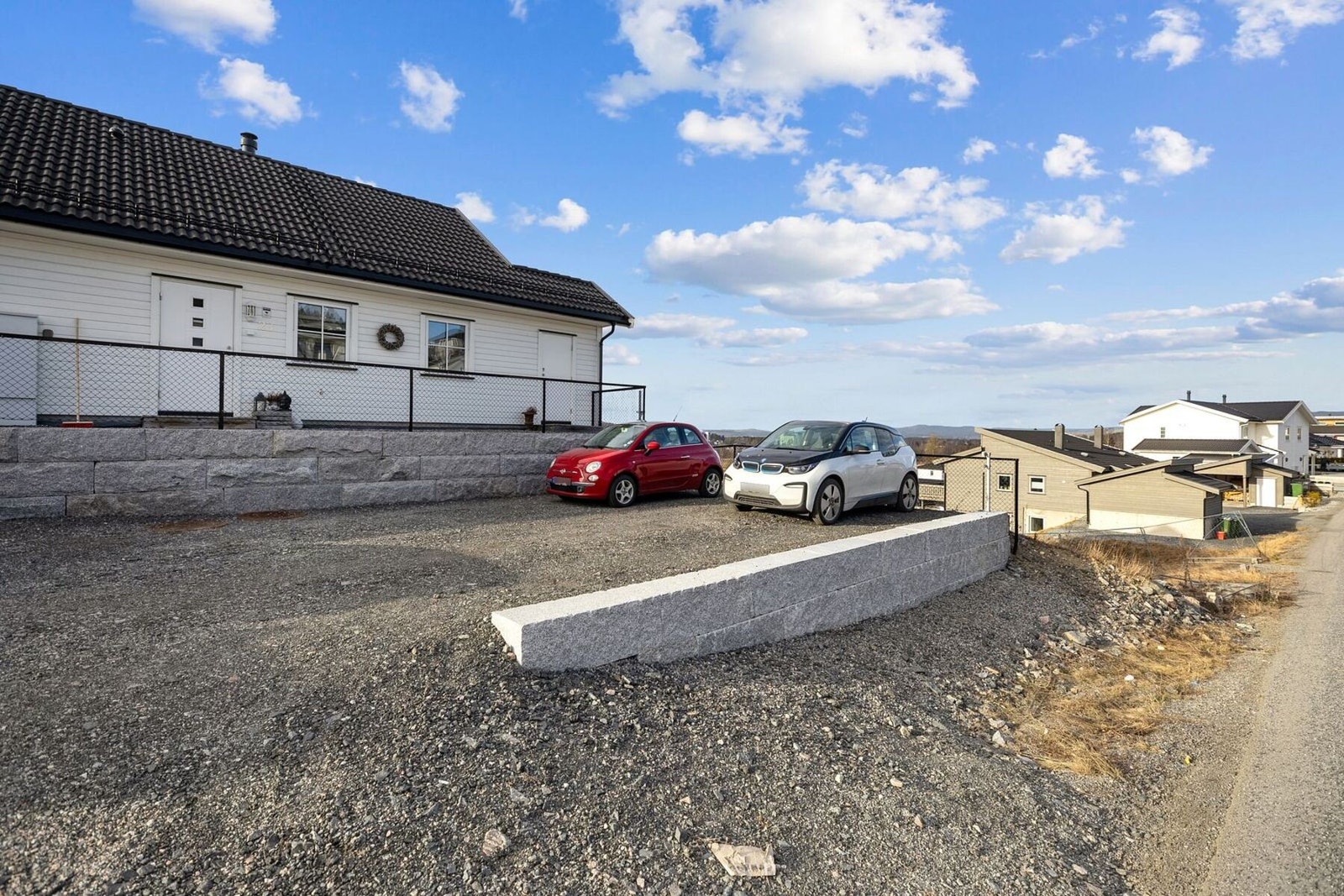 Det er parkering på gruslagt gårdsplass. Galleribilde
