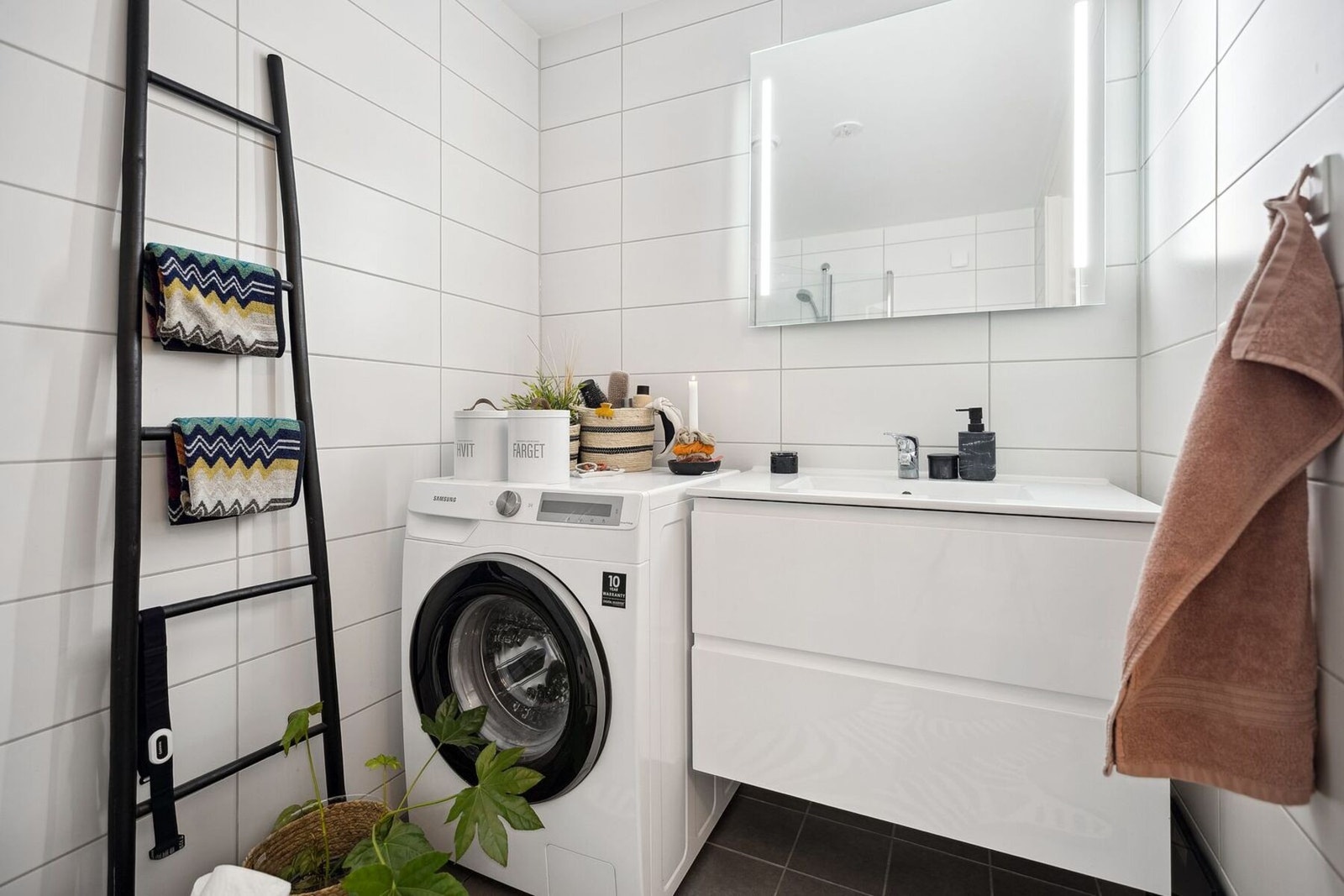Badet er innredet med vegghengt servantskap med heldekkende servant, speil med belysning, dusjnisje med innfellbare glassdører, vegghengt toalett og opplegg for både vaskemaskin og tørketrommel. Galleribilde