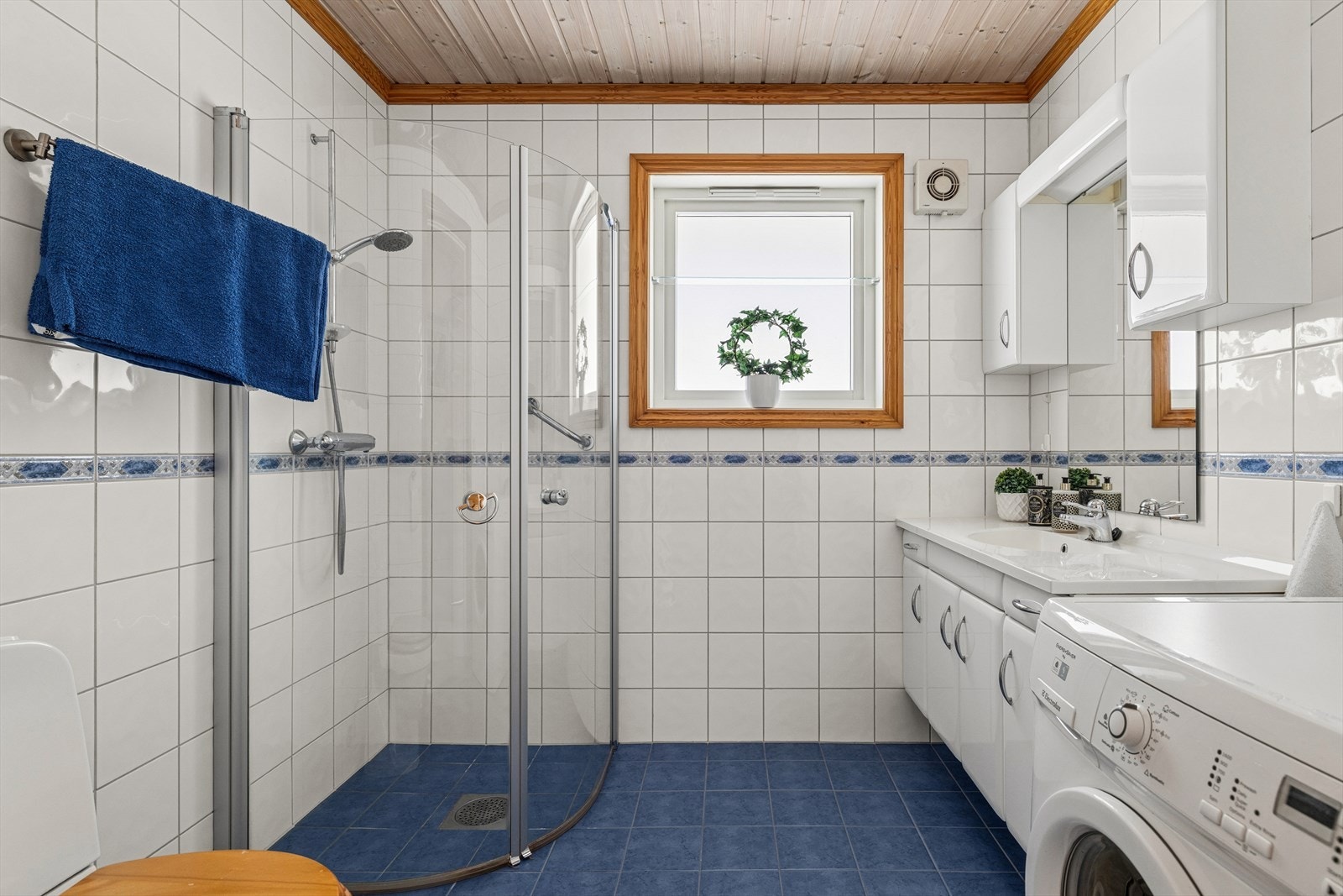 Flislagt bad med varmekabler i gulvet for ekstra komfort. Rommet er innredet med dusjhjørne med glassdører og har praktisk opplegg for vaskemaskin. Galleribilde