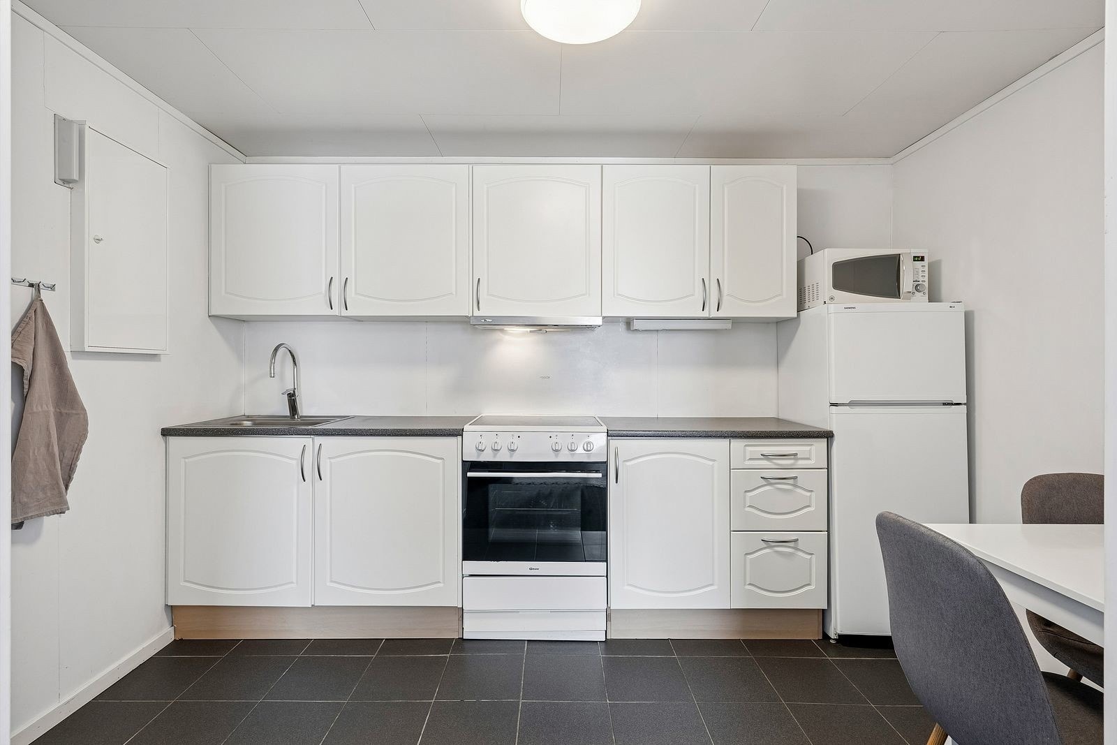 Kjøkken med kjøleskap og komfyr/koketopp.