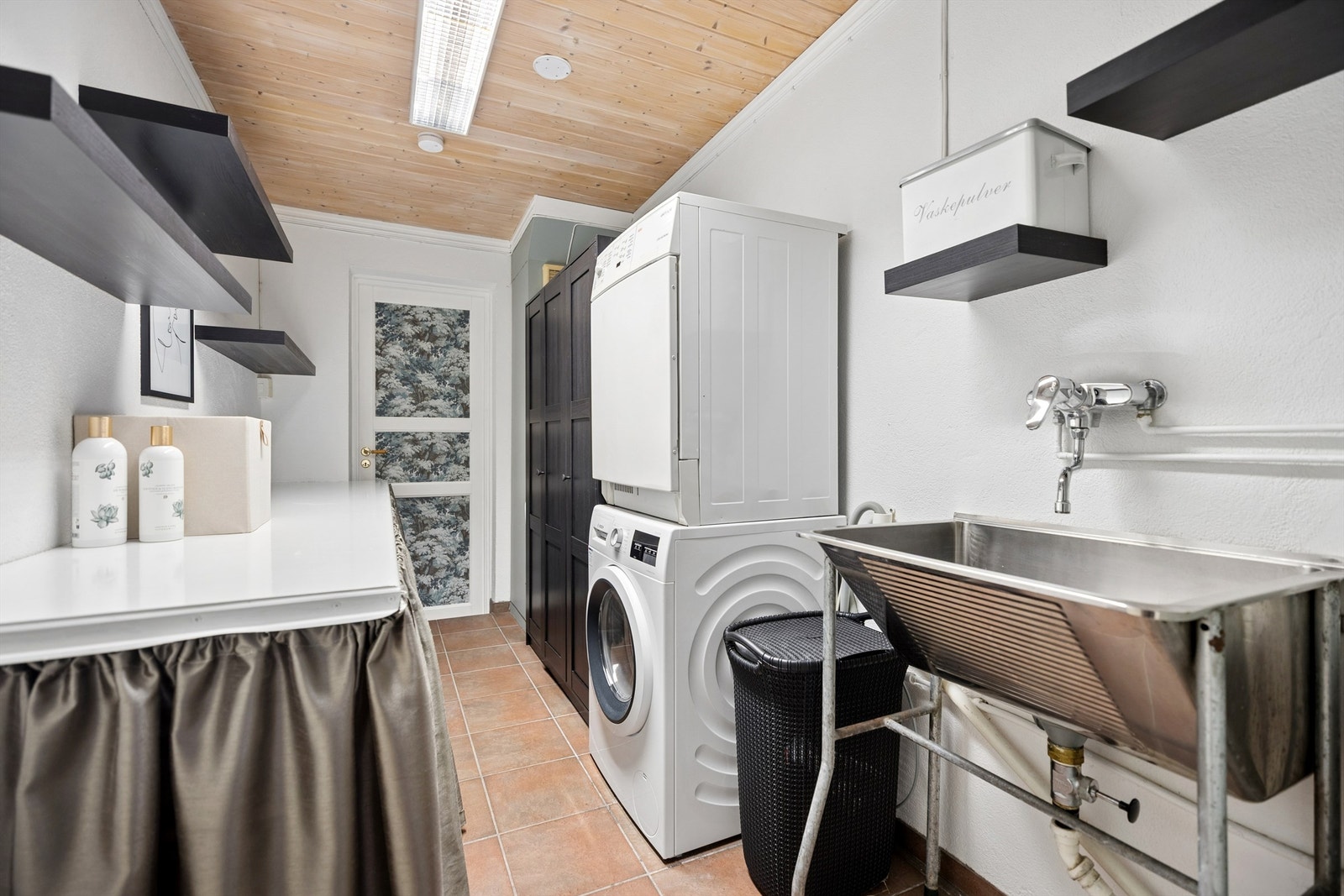 Stort og praktisk vaskerom i u. etasje med utslagsvask i rustfritt stål og opplegg for vaskemaskin og tørketrommel. Galleribilde