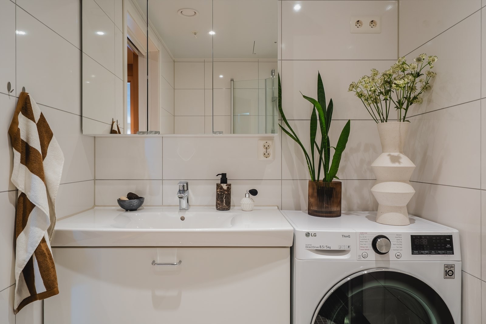 Moderne innredning, oppbevaring i speilskap, og opplegg for vaskemaskin. Galleribilde