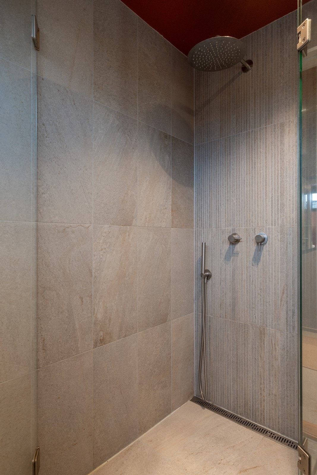 Rommet har flislagte gulv, fliser og malte flater på vegger, elektriske varmekabler, nedsenket dusjsone og vegghengt toalett. Galleribilde