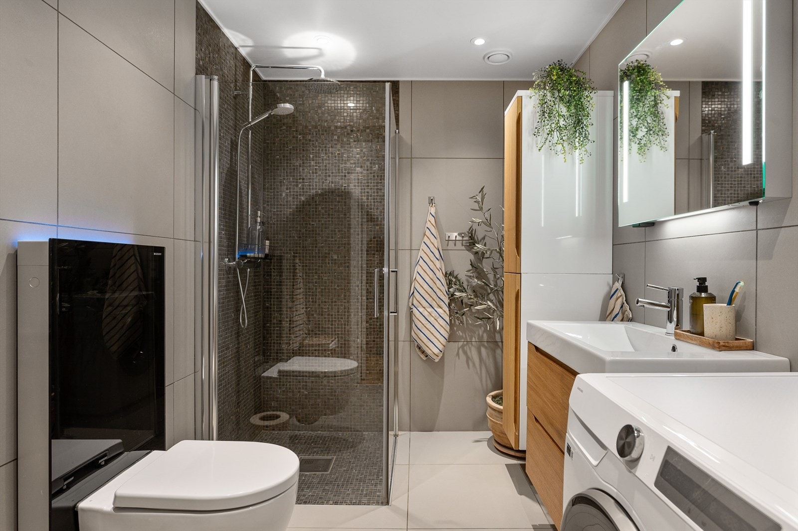 Heldekket flislagt bad med fliser på vegger og gulv, vannbåren gulvvarme og dusjhjørne med glassvegger. Galleribilde