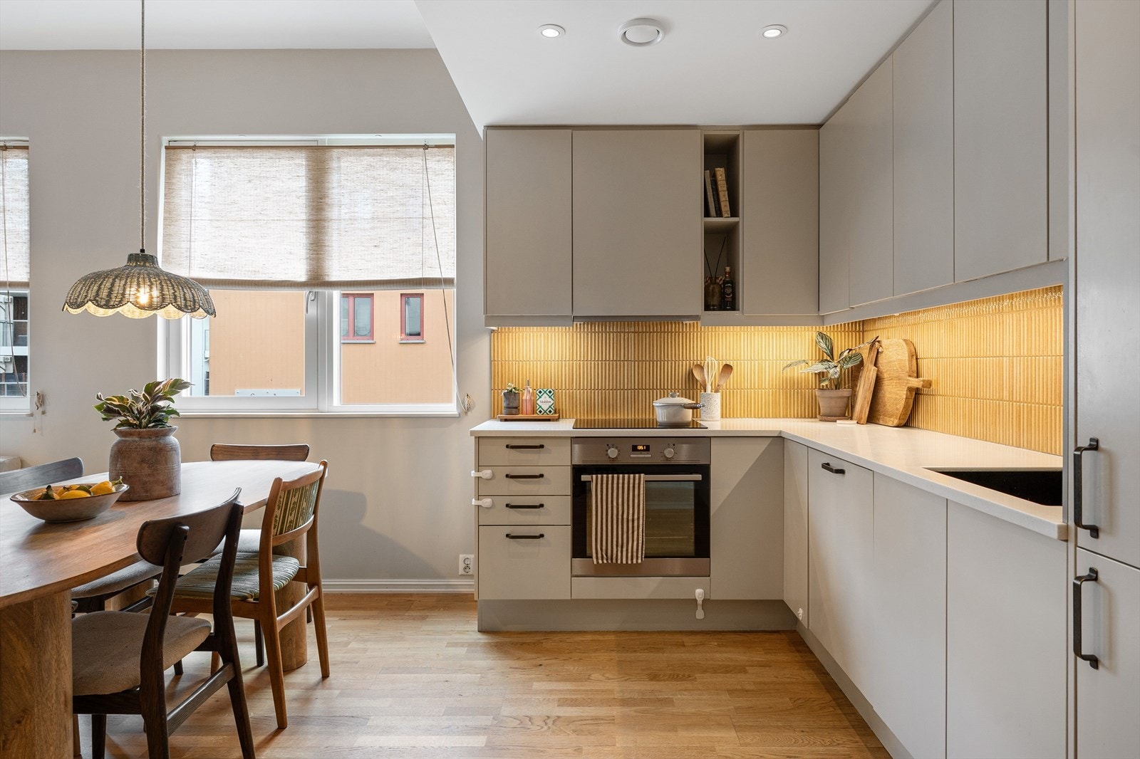 Flis mellom benk og overskap, samt kjøkkenventilator med avtrekk. Benkeplate, platetopp og flis ble oppgradert i 2023. Galleribilde