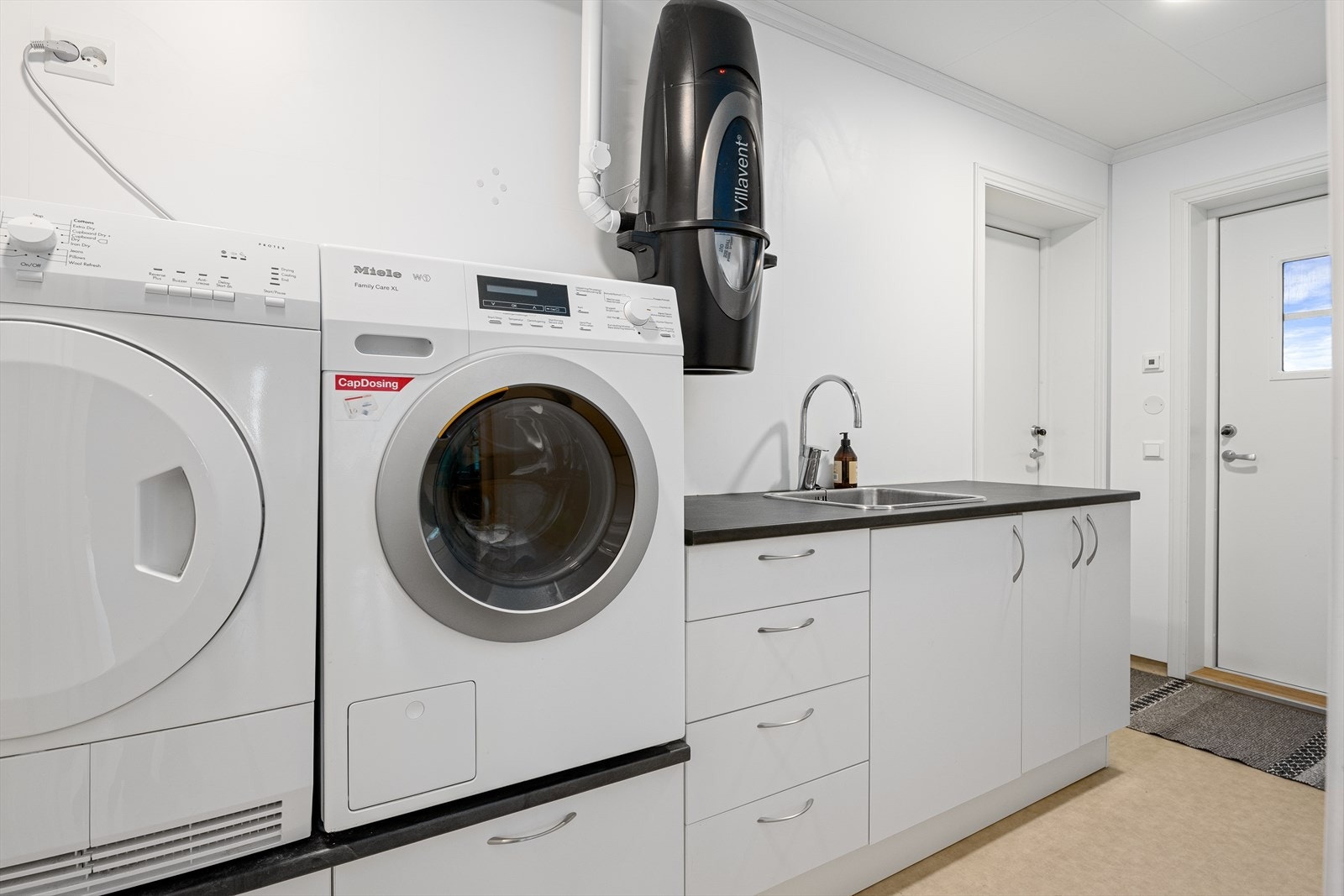 Her finner man innredning med benkeplate og skap, utslagsvask nedfelt i benkeplate og opplegg/plass for vaskemaskin og kondenstørketrommel i ergonomisk arbeidshøyde. Galleribilde