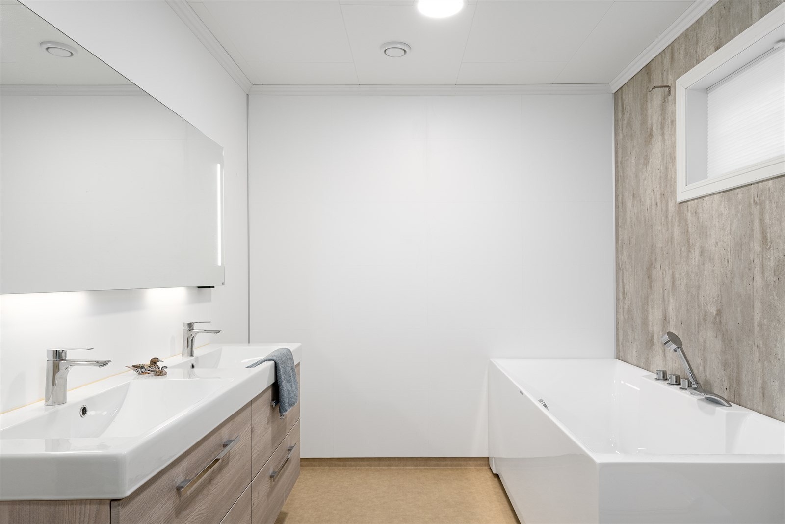 Rommet har innredning med dobbel servant nedfelt i servantskap, speil med lys, vegghengt toalett lekkasjesikret med drensutkast, dusjhjørne med glassdører og badekar. Galleribilde