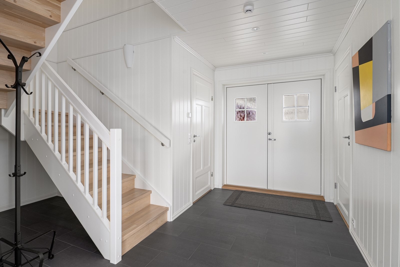 Her har man en romslig gang/hall med god plass til oppbevaring av yttertøy. Fliser på gulv. Galleribilde