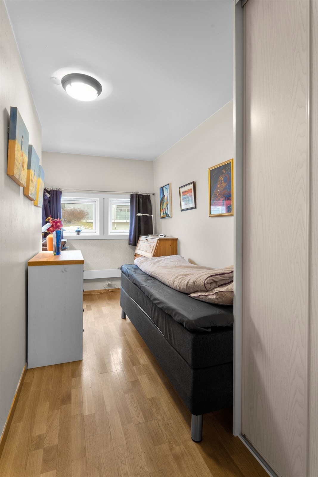 Skyvedørsgarderobe gir effektiv oppbevaring i rommet. Store vinduer slipper inn naturlig lys og gir utsikt til uteområdet. Galleribilde