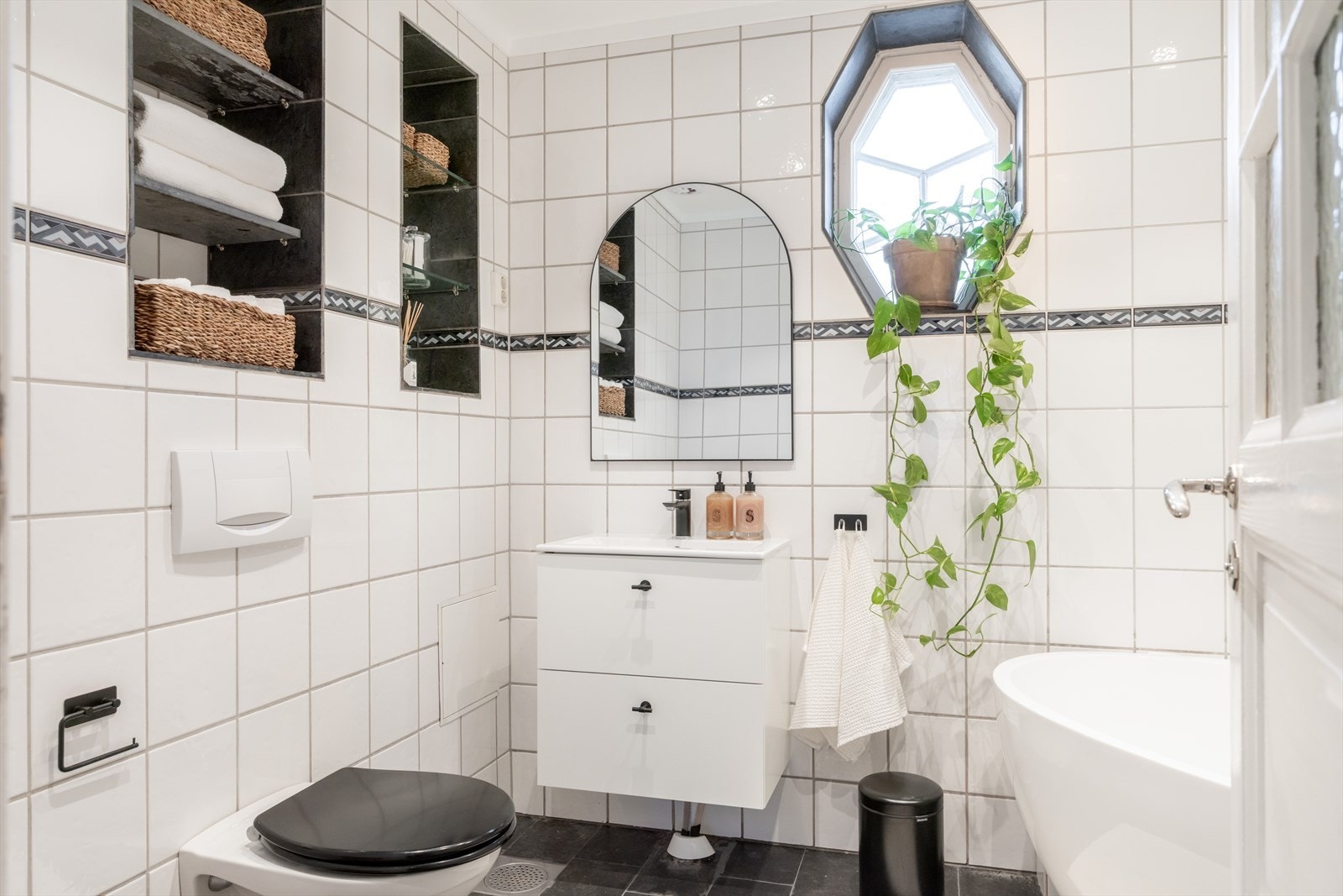 Romslig bad, innredet med hjørnebadekar med dusjløsning, vegghengt toalett og servant. Galleribilde