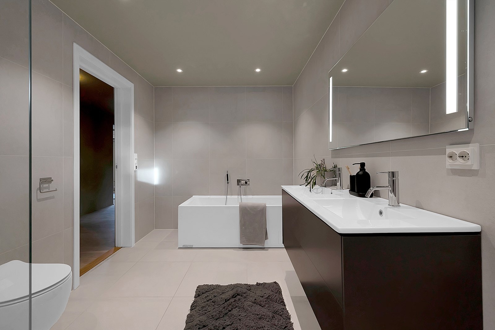 Romslig baderom med moderne innredninger, downlights, badekar, dusjhjørne og vegghengt toalett. Galleribilde