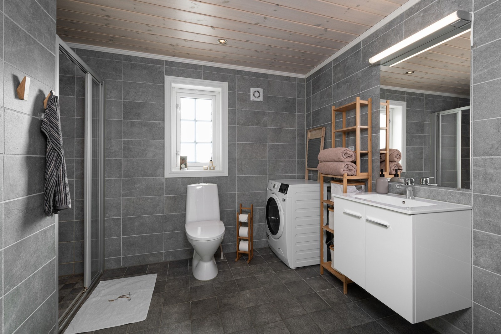 Bad er innredet med dusjnisje, servantinnredning, toalett og opplegg for vaskemaskin. Galleribilde