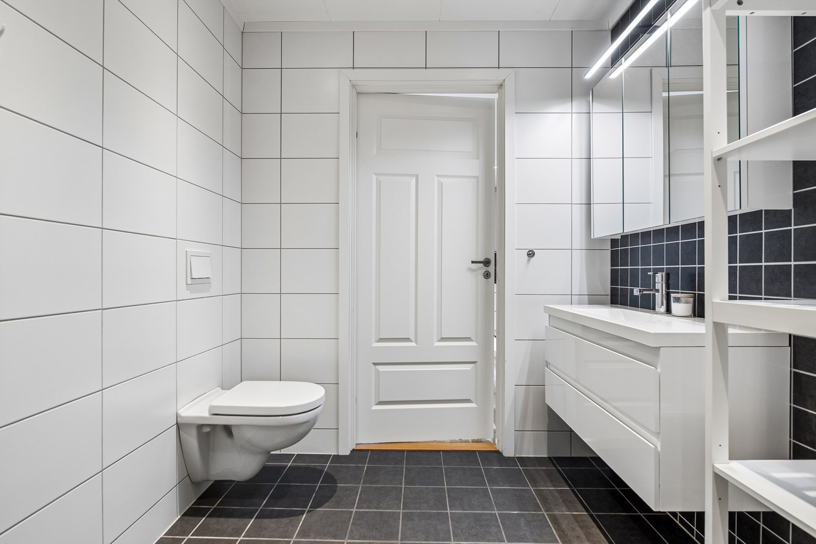 Badet er innredet med vegghengt toalett, dusjhjørne og har opplegg for vaskemaskin. Galleribilde