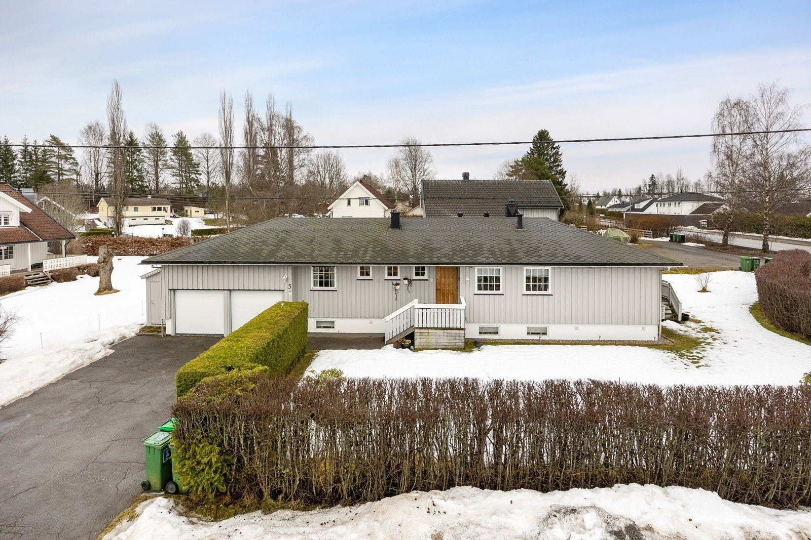 Boligen ligger på en romslig hjørnetomt med velstelt hekk og stor gressplen for lek Galleribilde