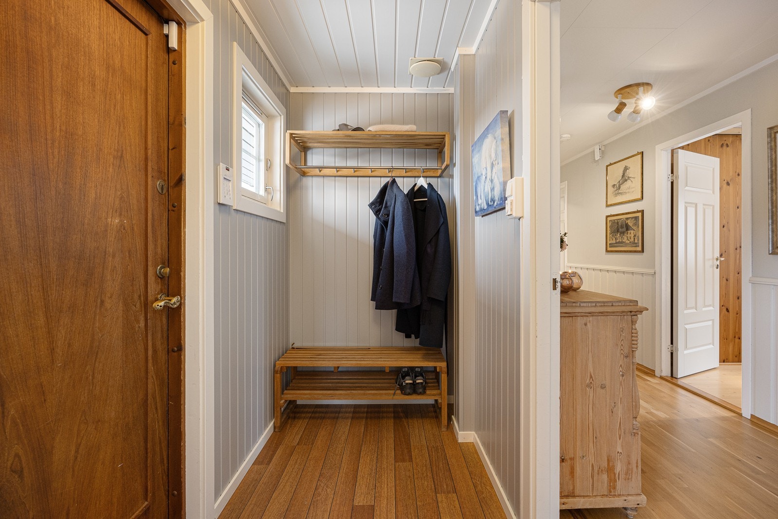 Vel inne har boligen en liten entré med gråmalte paneler i taket og på veggene. Her passer det fint å innrede med knagger og skohyller Galleribilde