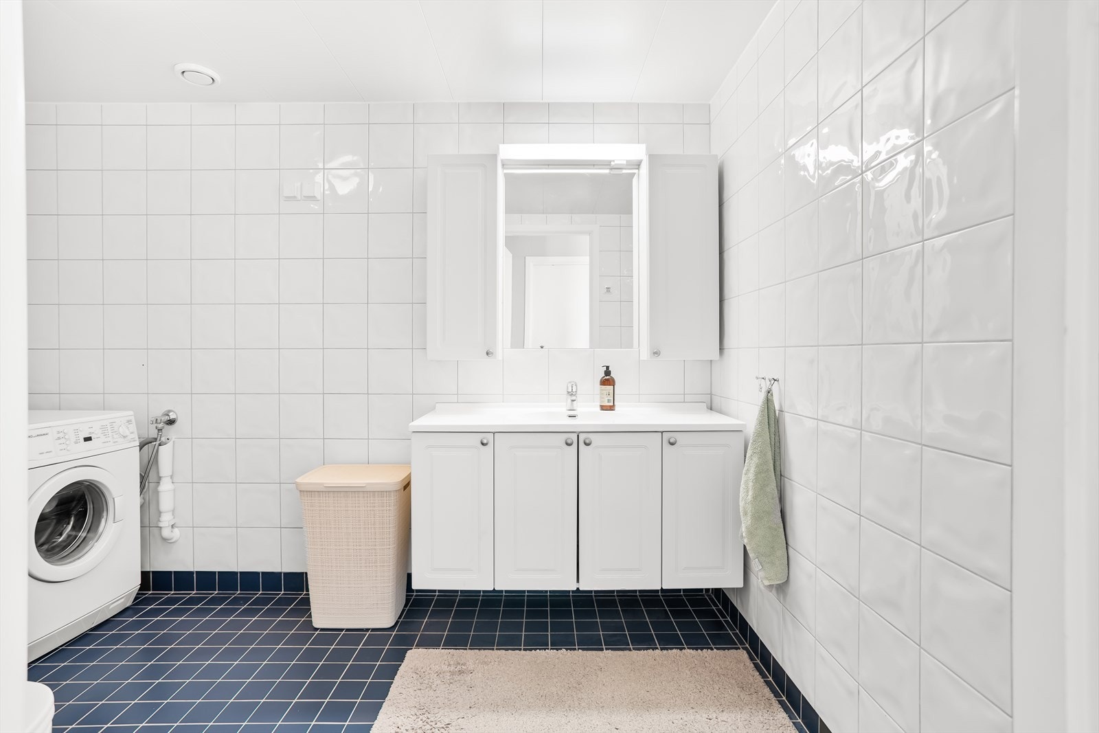 Badet har flislagt gulv med varmekabler, servantskap og speilskap med belysning. Galleribilde
