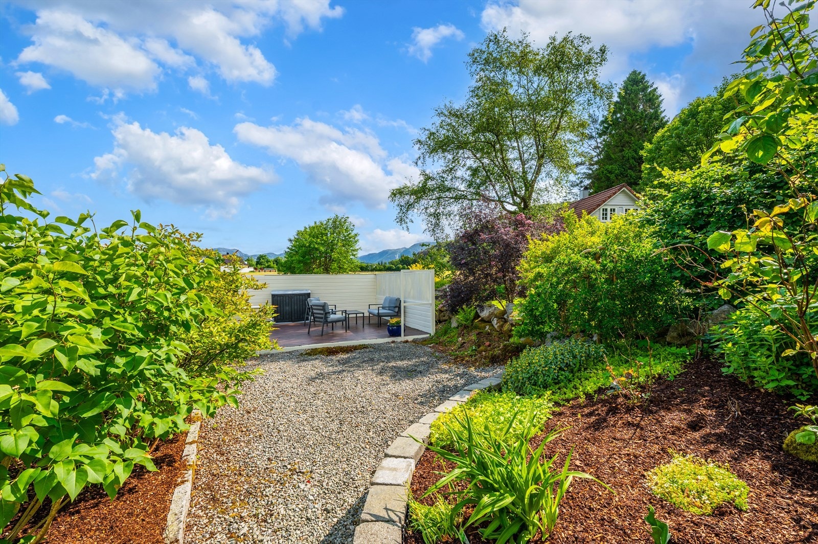 Gruslagt gangvei leder til en skjermet uteplass med sittegruppe. Galleribilde