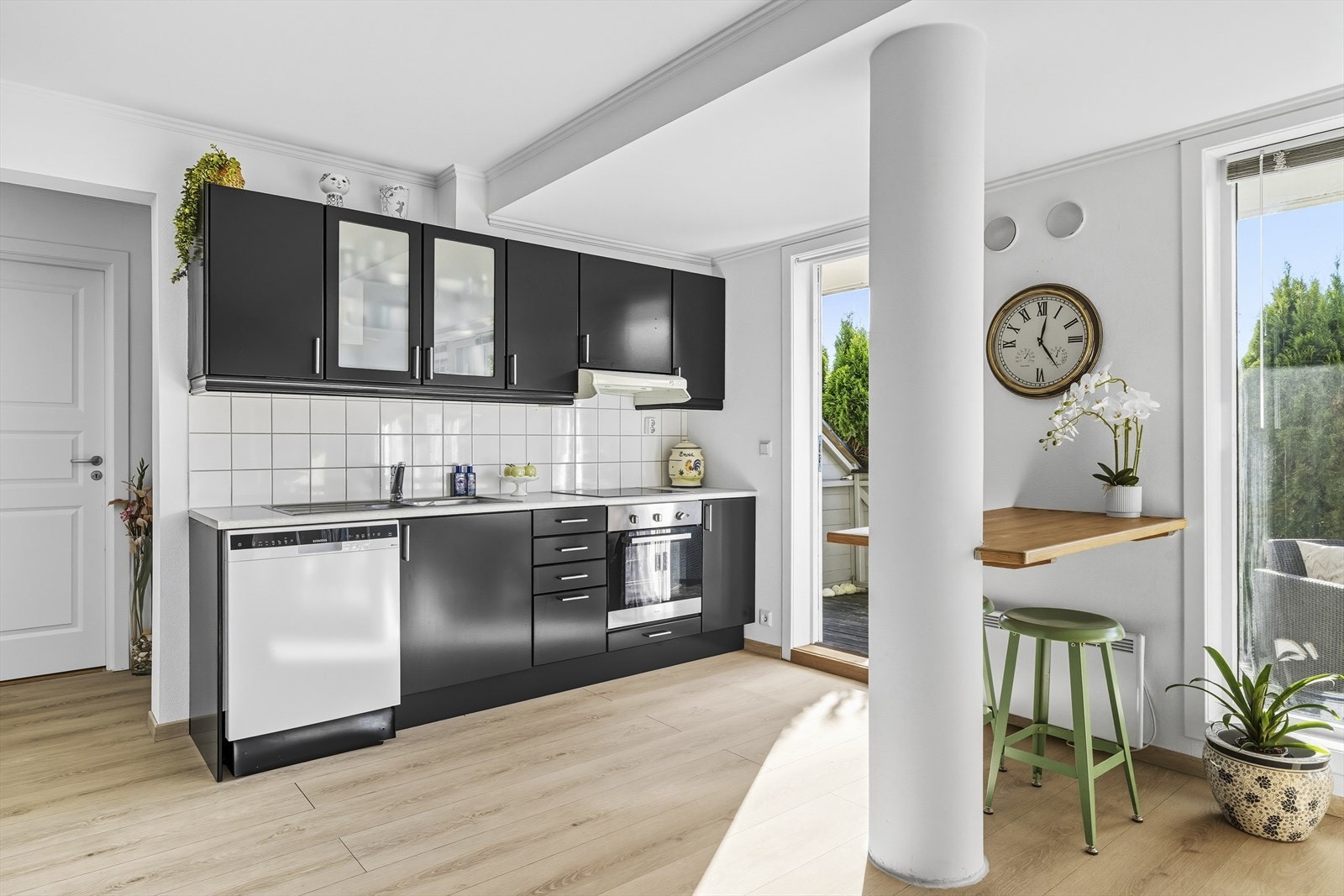 Kjøkkenet er i åpen løsning med stuen. Her er det en innredning med malte, slette fronter i sort farge og benkeplate i laminat. Galleribilde