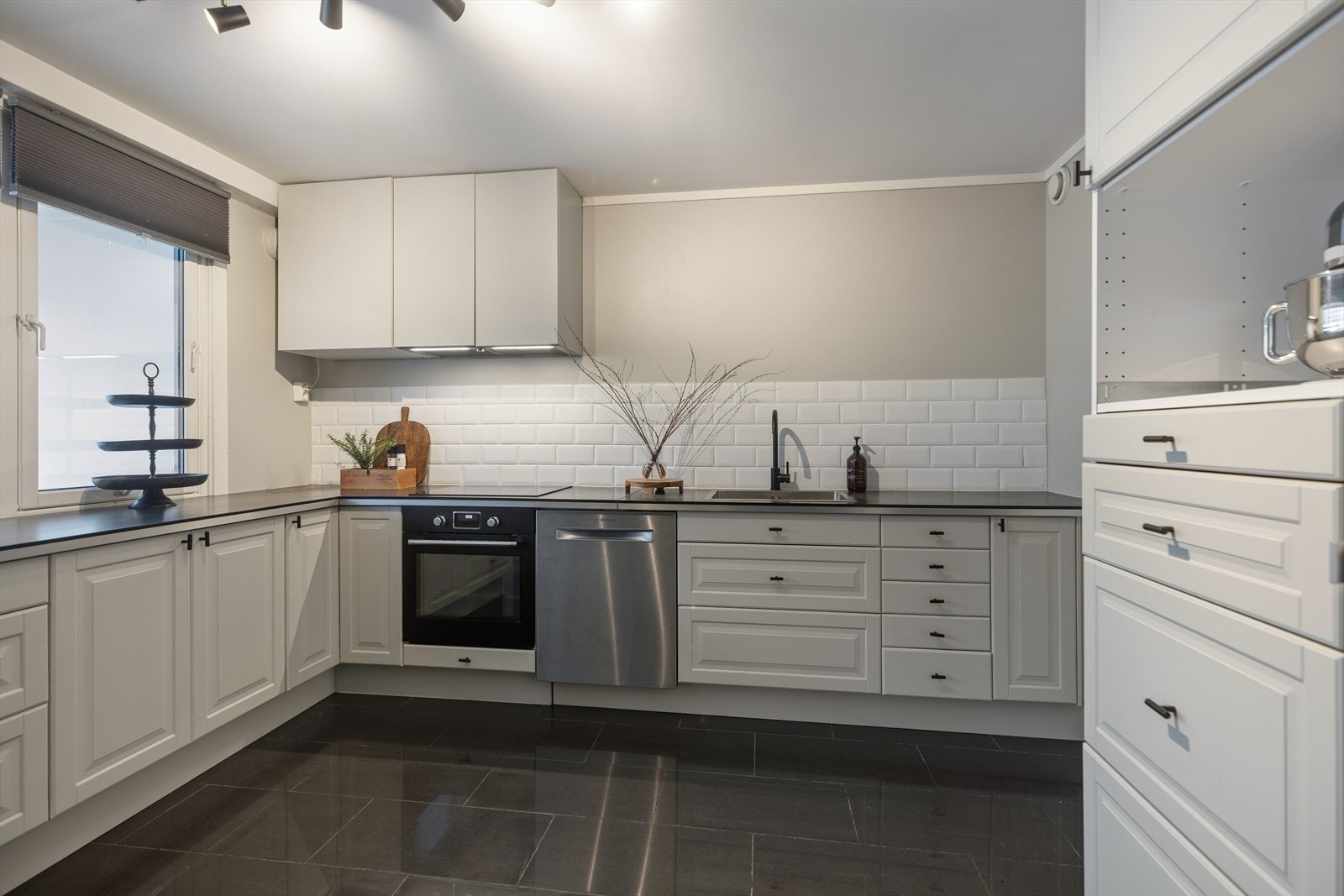 Kjøkkeninnredningen har profilerte fronter, laminatbenkeplate og fliser over benken. Galleribilde