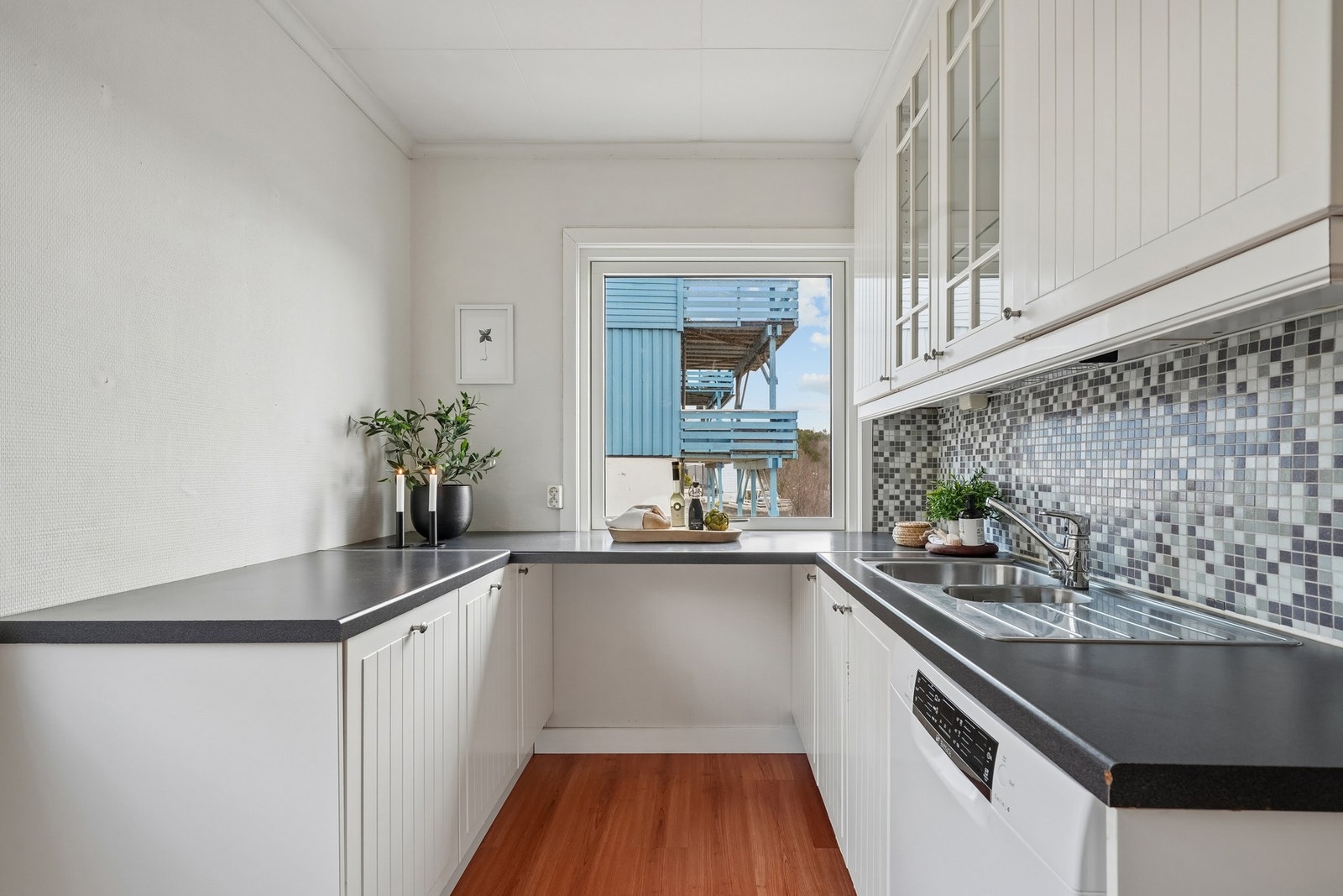 Det er mosaikkfliser på vegg over benkeplate. Galleribilde