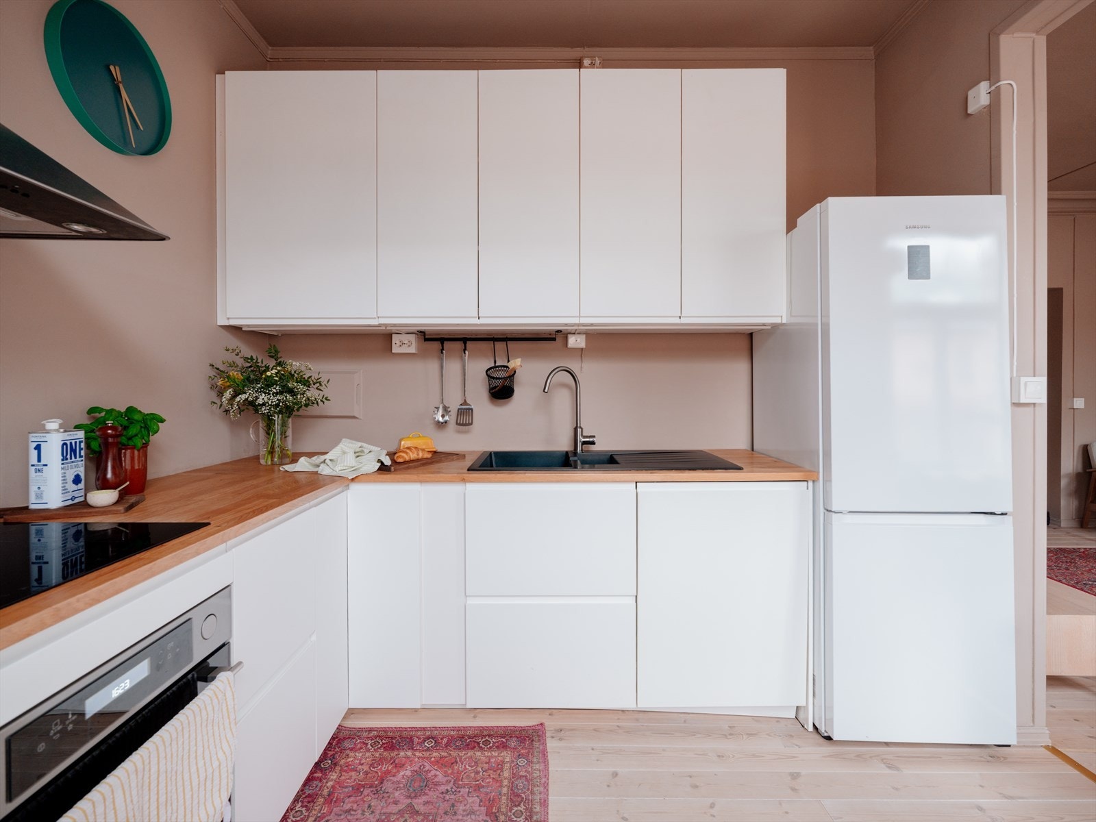 Innredningen har en tidløs utforming bestående av hvite matte fronter med integrert grep og benkeplate i tre. Galleribilde