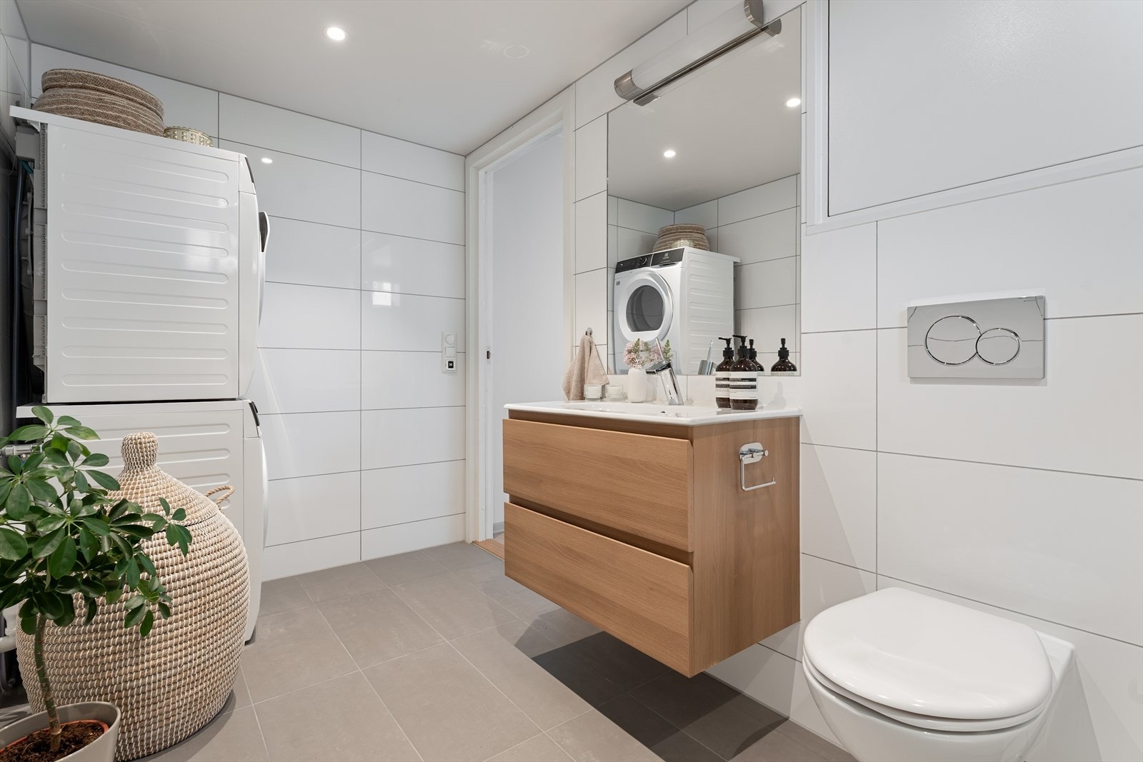 Videre er badet utstyrt med servant i helstøpt plate, vegghengt toalett med innebygget sisterne og opplegg for vaskemaskin, noe som gjør rommet både praktisk og komfortabelt i bruk. Galleribilde