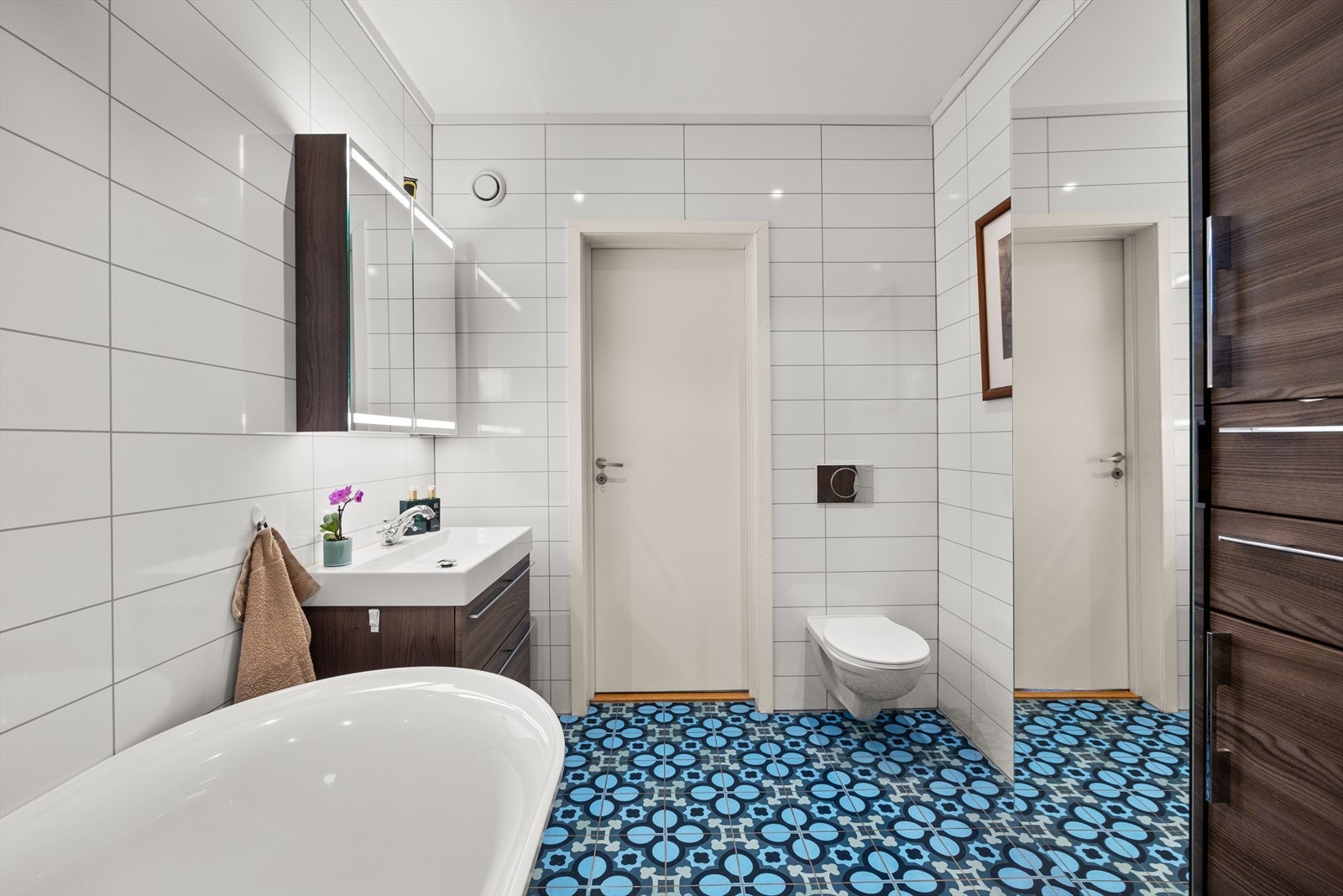 Videre har badet vegghengt toalett, servant med skuffer og speilskap med belysning. Badet har downlights i himling. Galleribilde