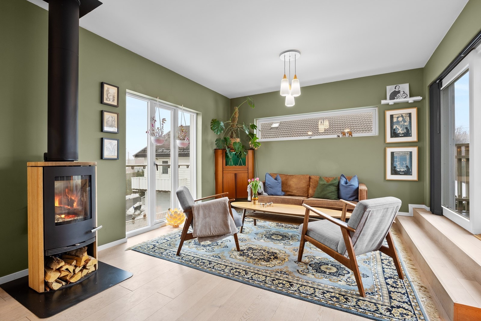 Stuen har parkett på gulv og slette vegger. Midt i stuen er det en peisovn. Videre er det trapp ut på balkongen. Galleribilde