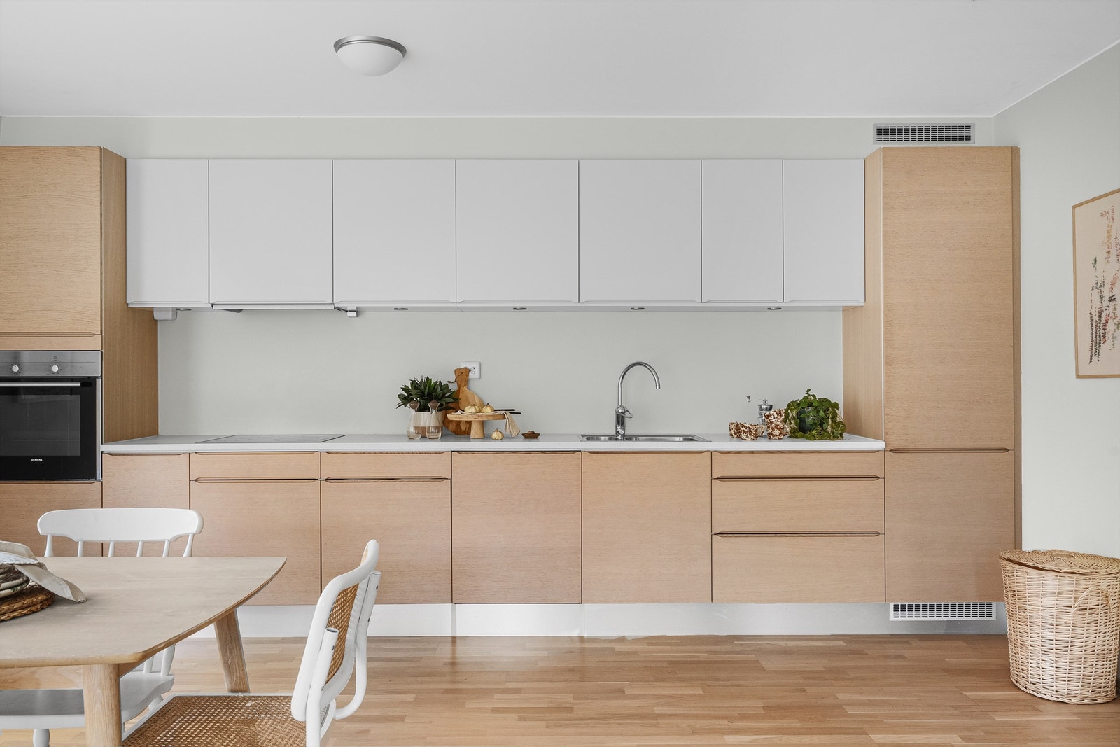 Kjøkkenet er i moderne og fint design med fronter i eik og hvitt. Lys benkeplate. Kjøkkeninnredning er fra HTH og det er integrerte hvitevarer, spotter under overskap og godt med benke - og skapplass. Galleribilde