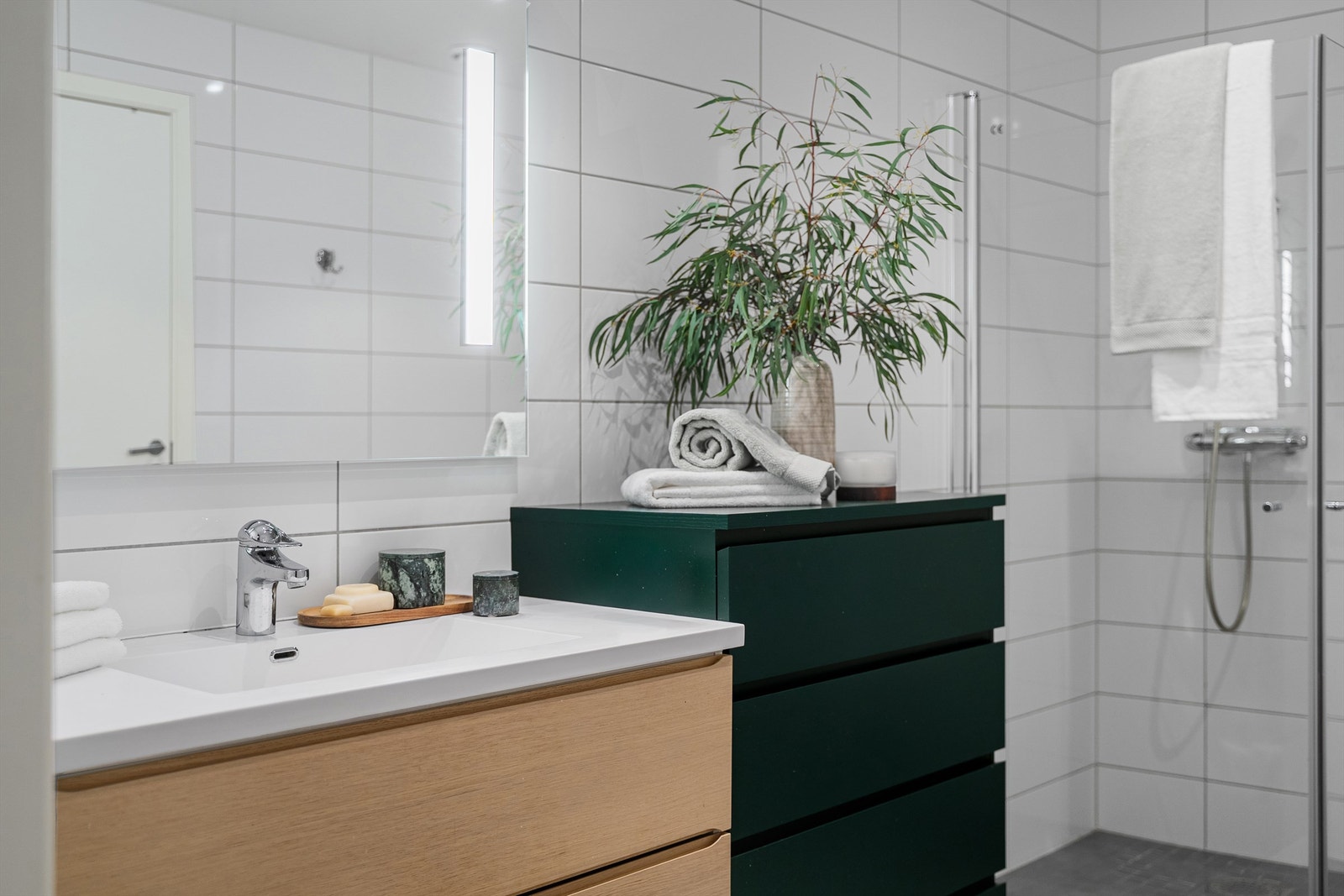 Bad er av meget god størrelse og er helfliset med varme i gulv. Det er dusjhjørne med innfellbare dører, vegghengt toalett og servant med oppbevaringsplass i skuffer. Stort speil på vegg. Galleribilde