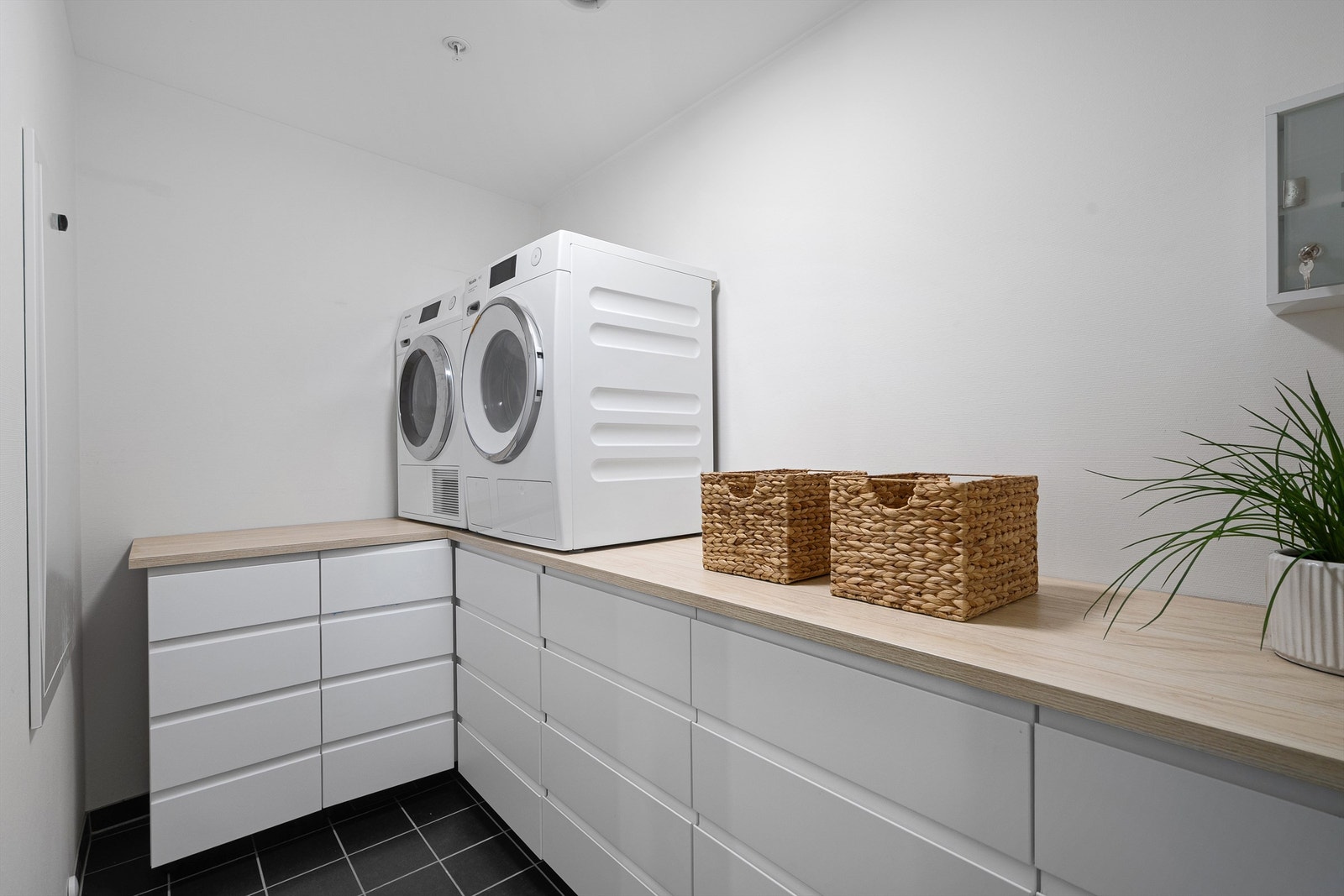 Her er det smarte løsninger med god oppbevaring i skuffer og benkeplate. Et drømmerom for mange. Opplegg for vaskemaskin og plass til tørketrommel. Galleribilde