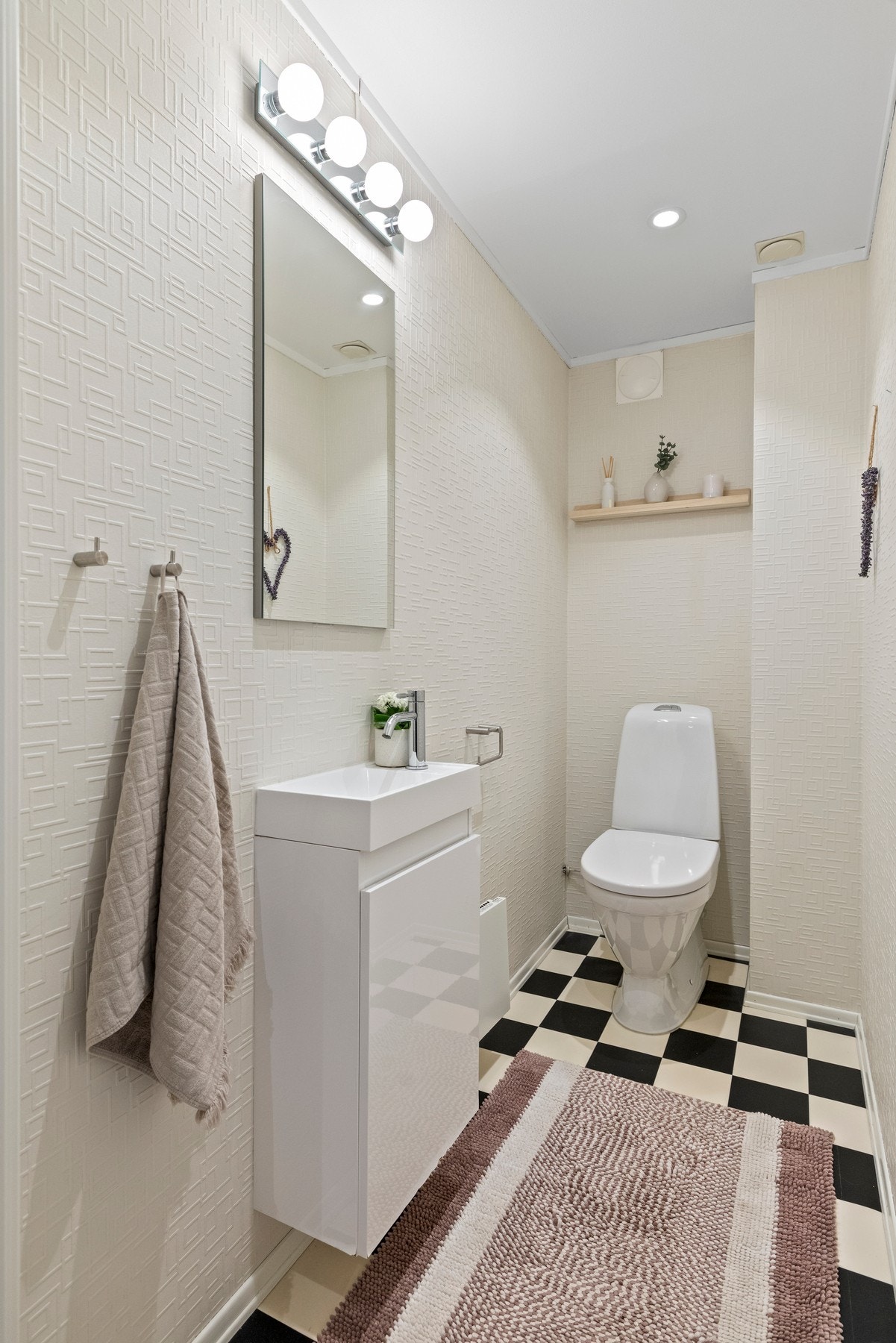 Praktisk toalettrom med servantinnredning, speil og dekorative vegg- og gulvflater. Galleribilde