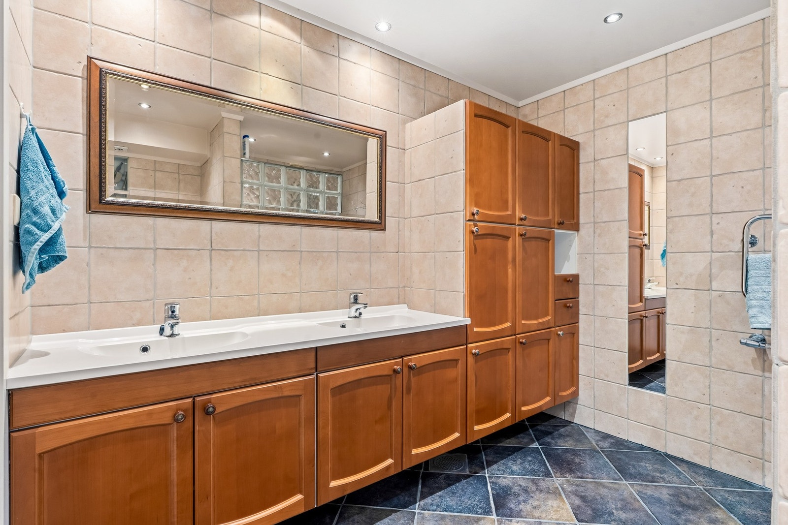 Flott flislagt familie bad fra 2002 med gulvvarme. Rommet har baderomsinnredning med to nedfelte servanter, veggmontert toalett og egen dusjsone avgrenset med glassbyggerstein. Det er håndklevarmer på vegg. På badet er det en elektrisk vifte som trekker u Galleribilde