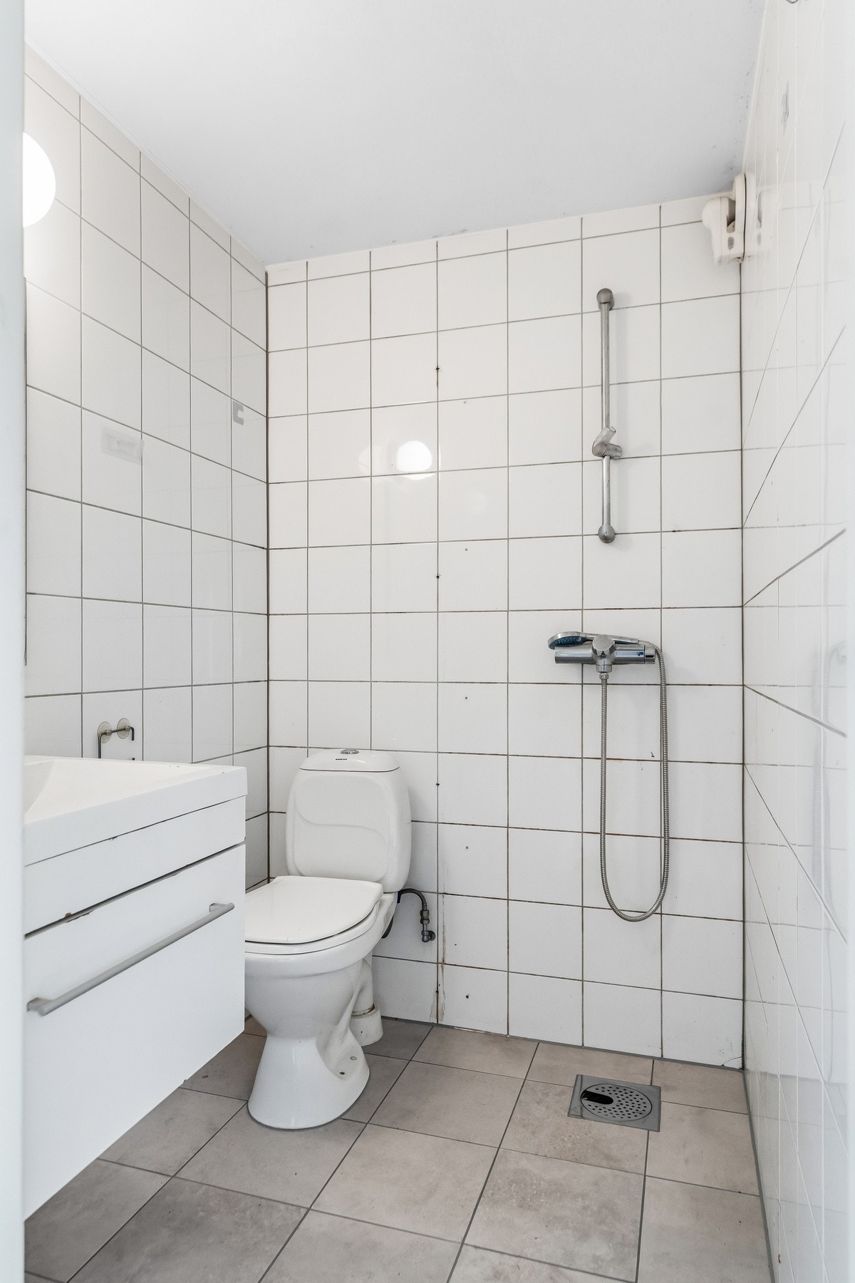 Hybelbad. Dusjbad med ny membran og gulvfliser i 2026. Rommet har baderomsinnredning med nedfelt servant i skuffeseksjon,ettgreps blandebatteri, gulvmontert toalett og dusj. Galleribilde