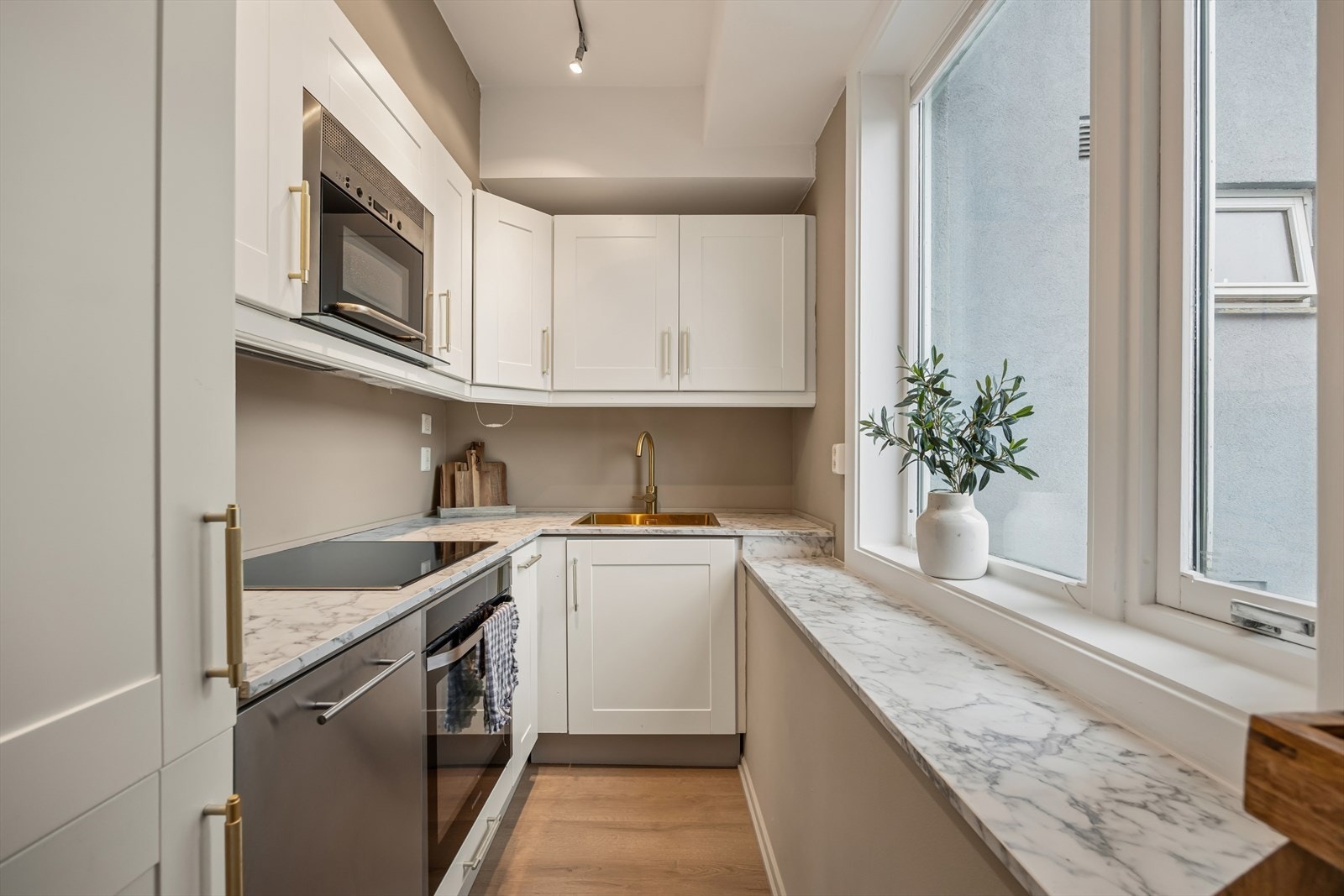 Kjøkkeninnredning med laminat benkeplate med nedfelt kum i rustfritt stål. Stekeovn, platetopp, mikrobølgeovn, kjøl/frys og oppvaskmaskin er integrert i innredningen. Galleribilde