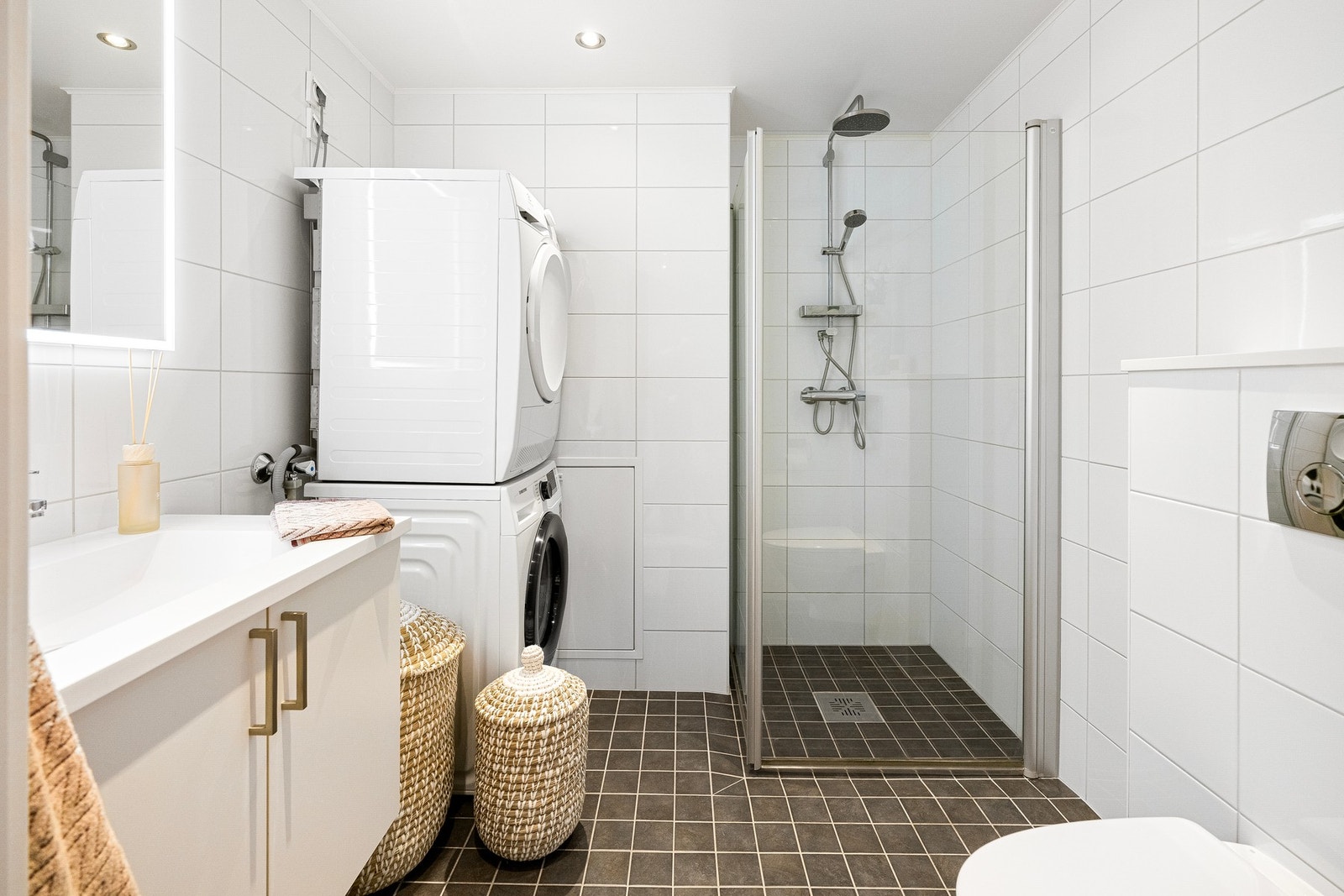 Badet har mørke fliser på gulvet med vannbåren gulvvarme og lyse fliser på veggene. Galleribilde