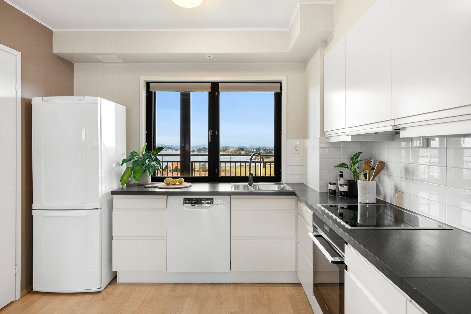 Kjøkkeninnredningen har hvite, slette fronter og laminert benkeplate med nedfelt oppvaskkum. Galleribilde